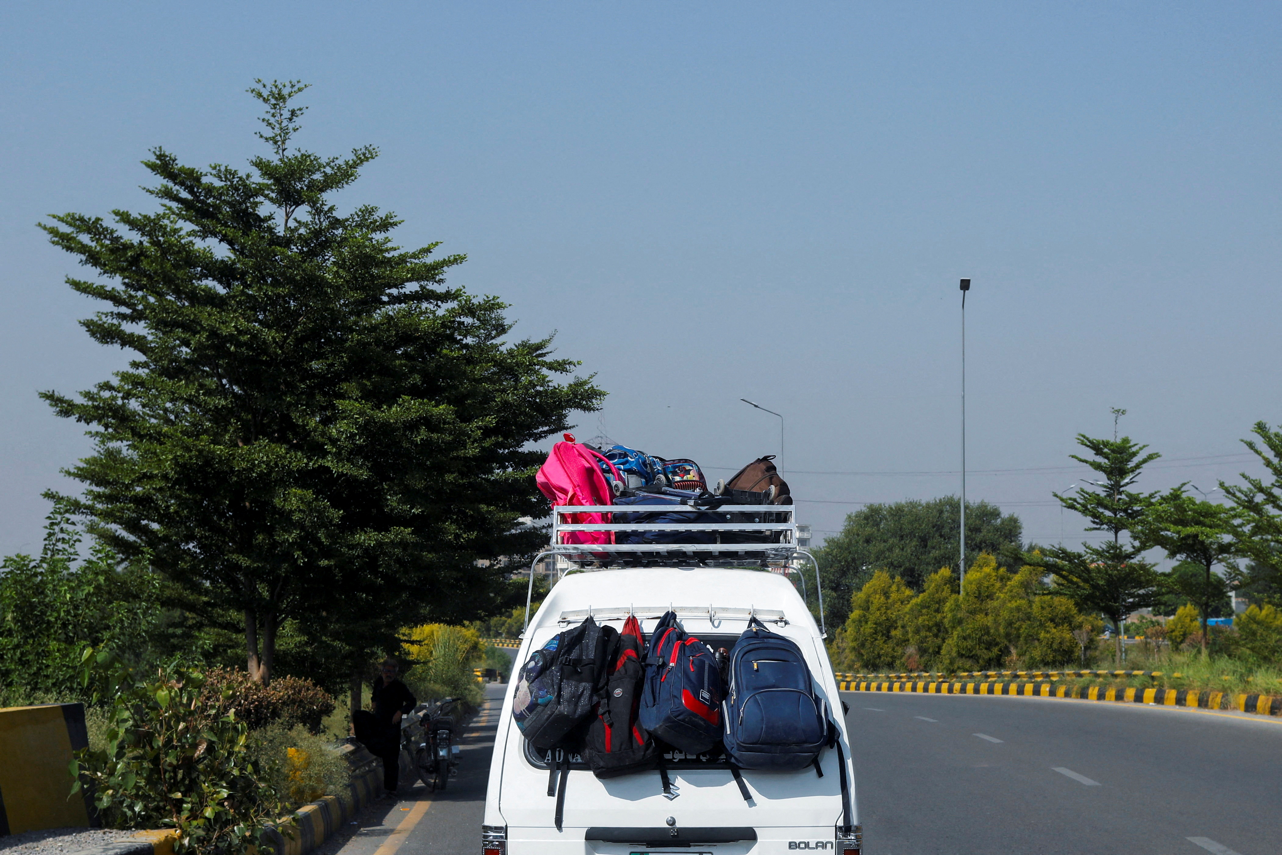 Bags belonging to students hang from the back of a school van, on a road in Rawalpindi, Pakistan
