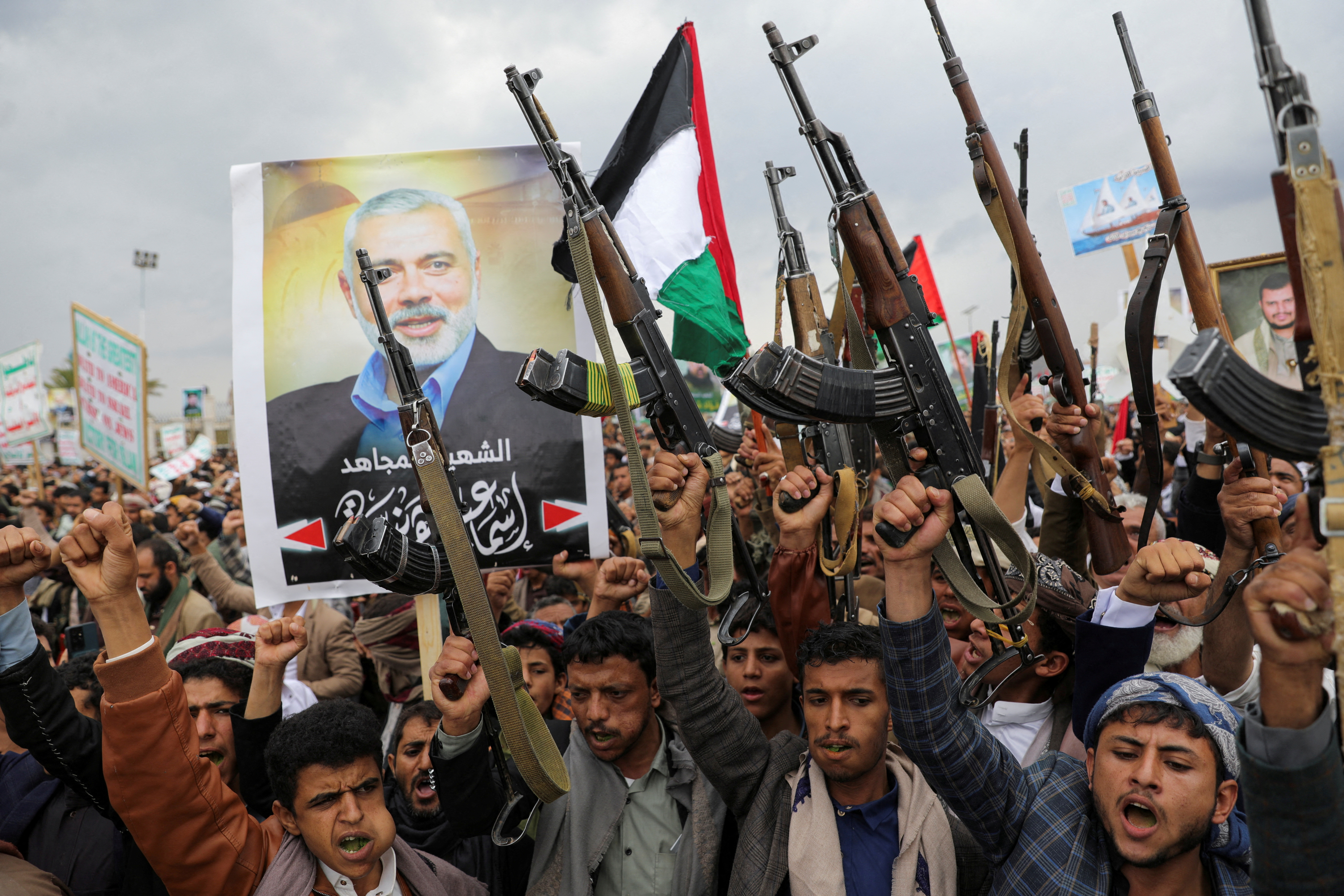 Protesters, mainly Houthi supporters, hold firearms next to a poster of assassinated Hamas chief Ismail Haniyeh, at the rally to show solidarity with Palestinians in the Gaza Strip, in Sanaa, Yemen, August 2, 2024.