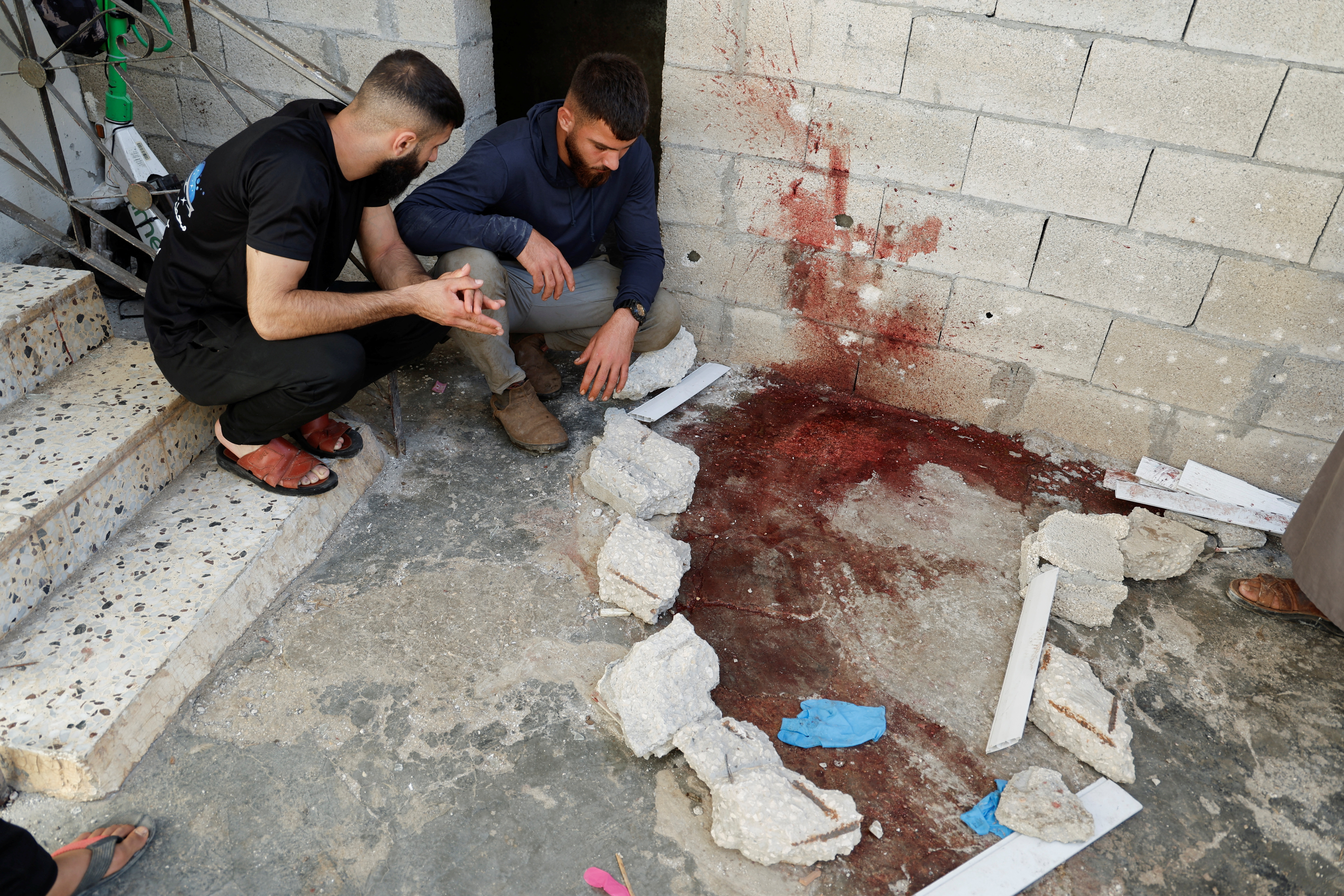 Palestinians react next to a bloodied ground at a house, during an Israeli raid, in Tubas