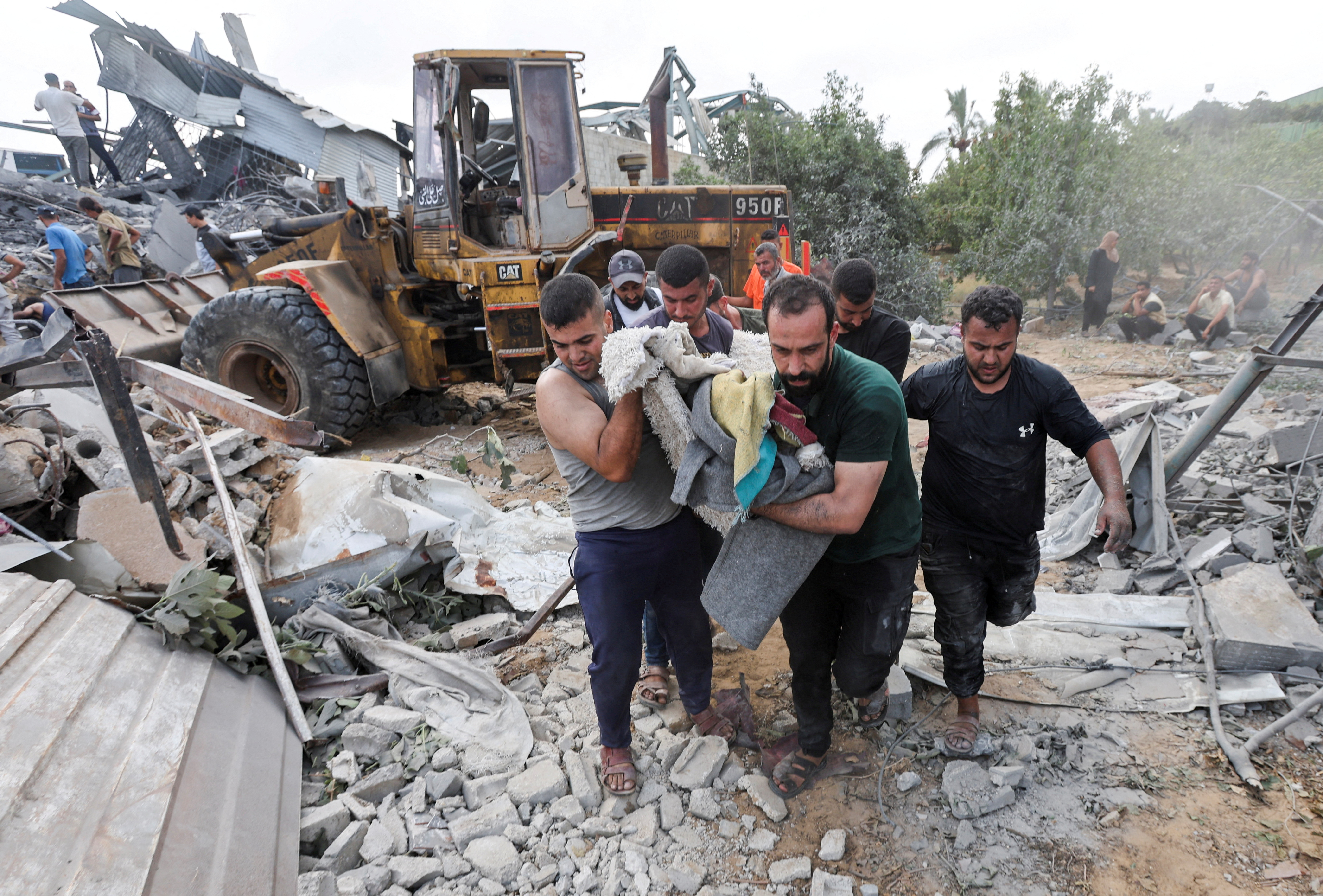 Palestinians carry a casualty at the site of an Israeli airstrike on a shelter housing displaced people, amid the conflict between Israel and Hamas, in central Gaza Strip, August 17, 2024. REUTERS/Ramadan Abed
