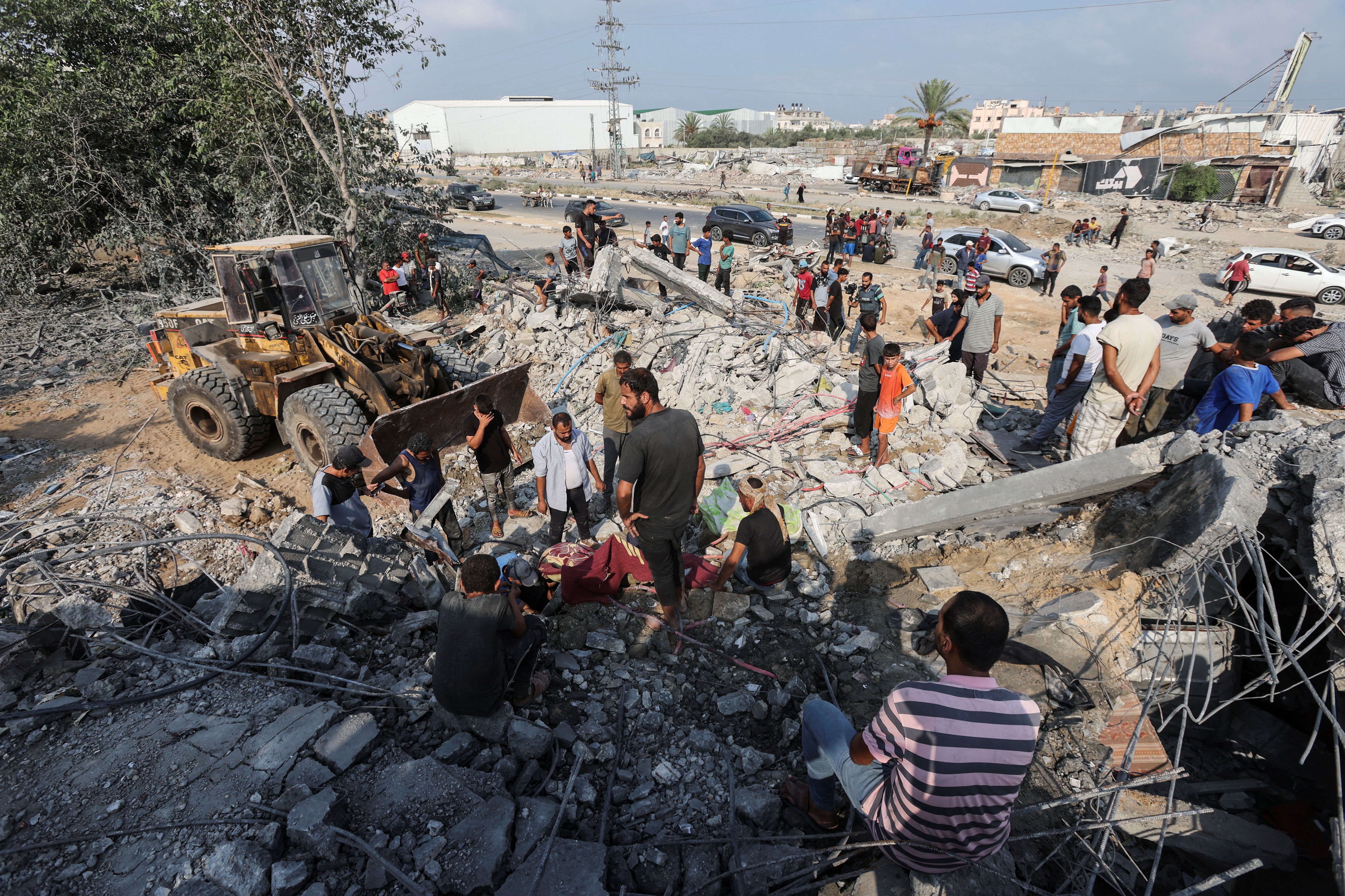 Palestinians stand at the site of an Israeli airstrike on a shelter housing displaced people, amid the conflict between Israel and Hamas, in central Gaza Strip, August 17, 2024. REUTERS/Ramadan Abed