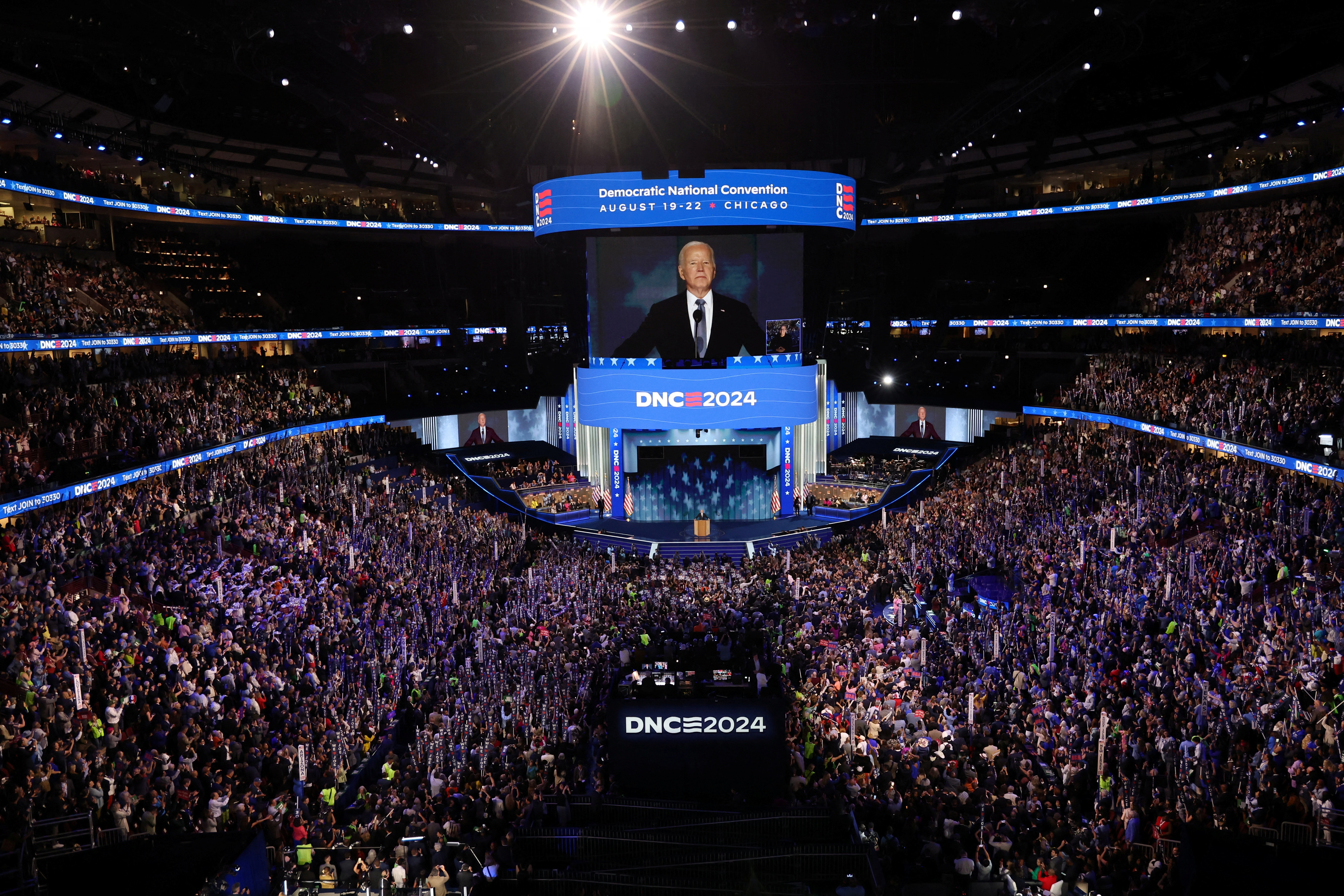 people fill up stadium with Biden's image on jumbotron screen