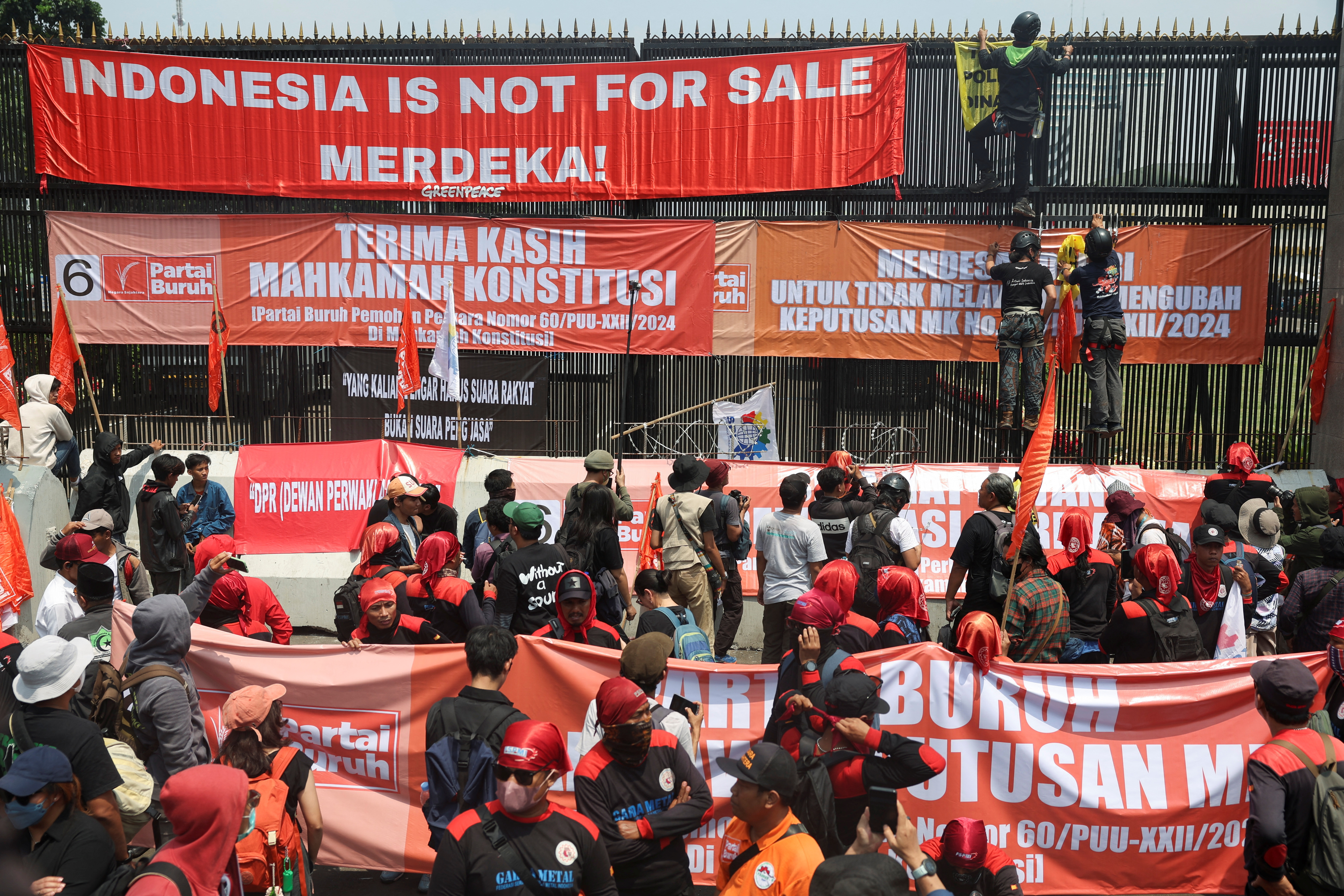 People attend a protest outside the Indonesian Parliament against the revisions to the country's election law