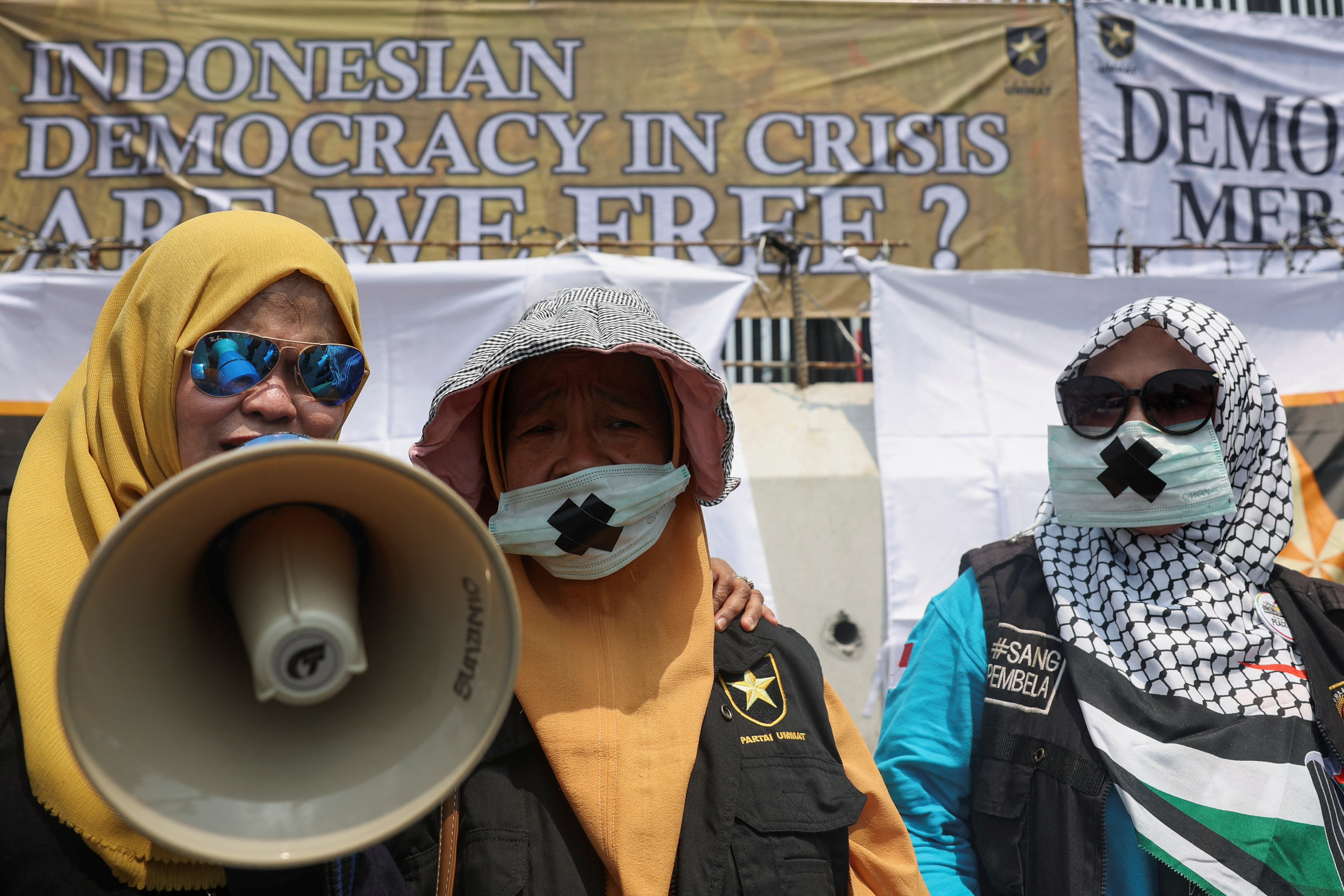 People attend a protest outside the Indonesian Parliament against the revisions to the country's election law