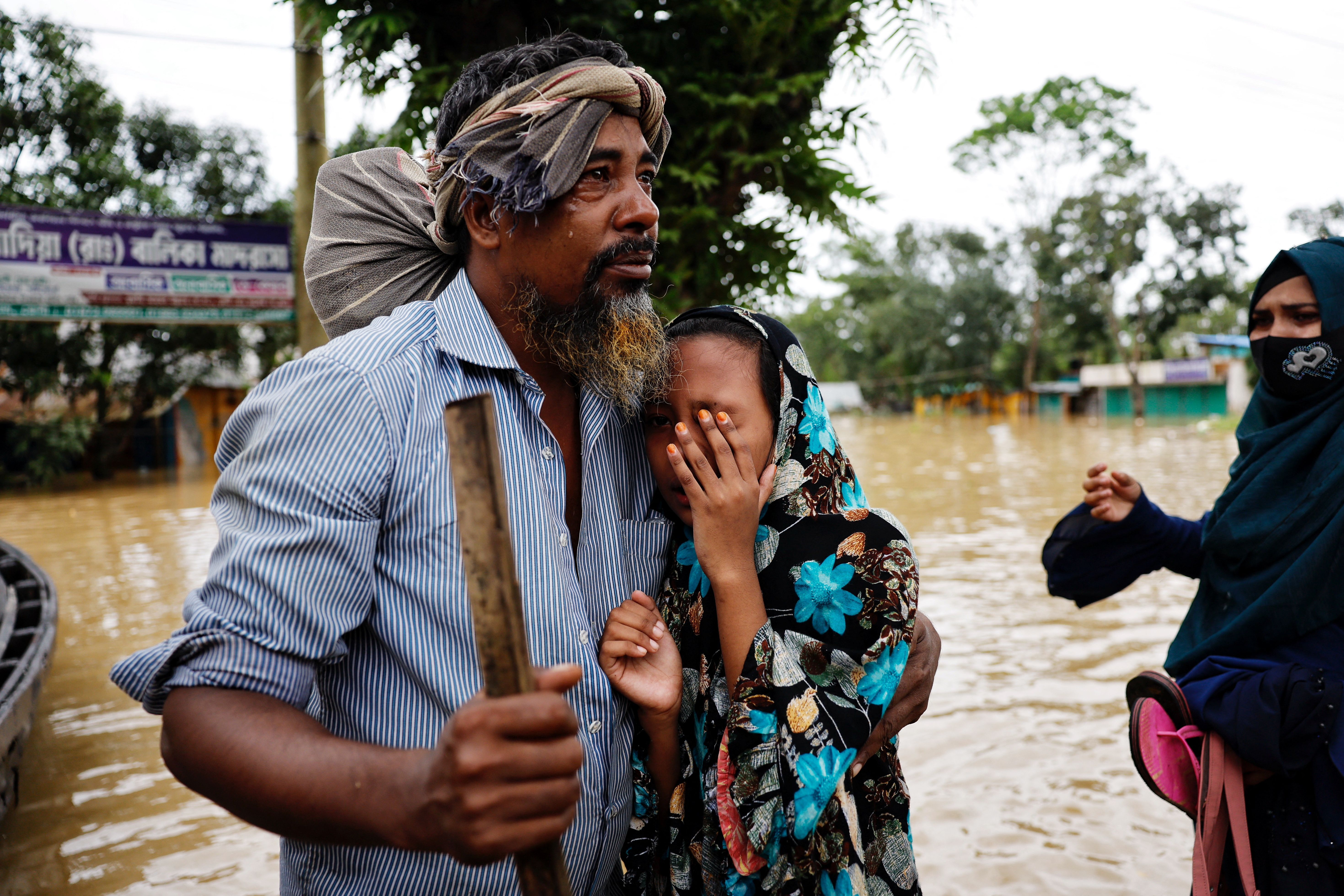 Saiful Islam cries after meeting his daughter Sadia Akter after four days as a severe flood hits the Lalpol area in Feni,