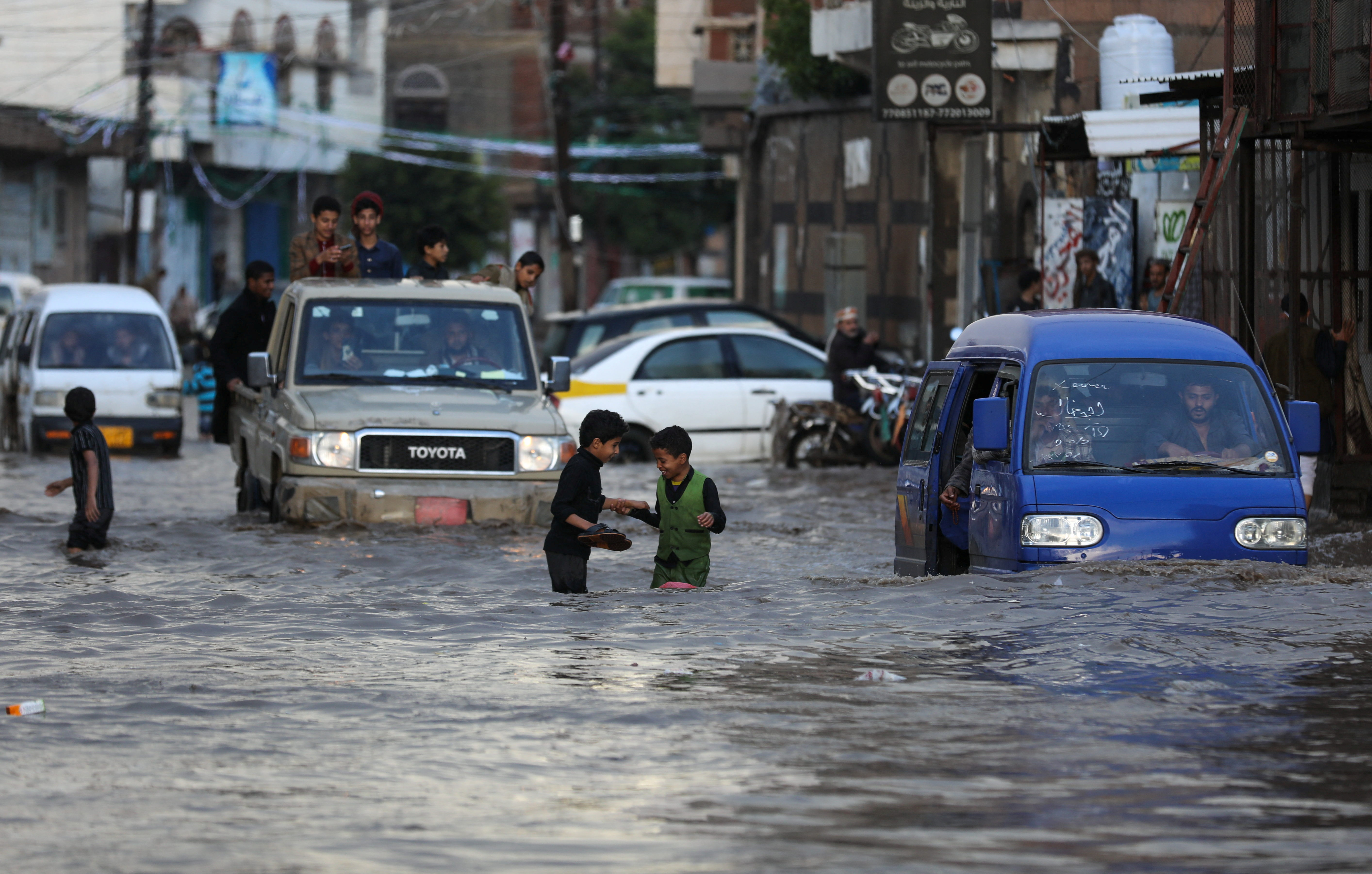 Boys play on a flooded street during heavy rains in Sanaa