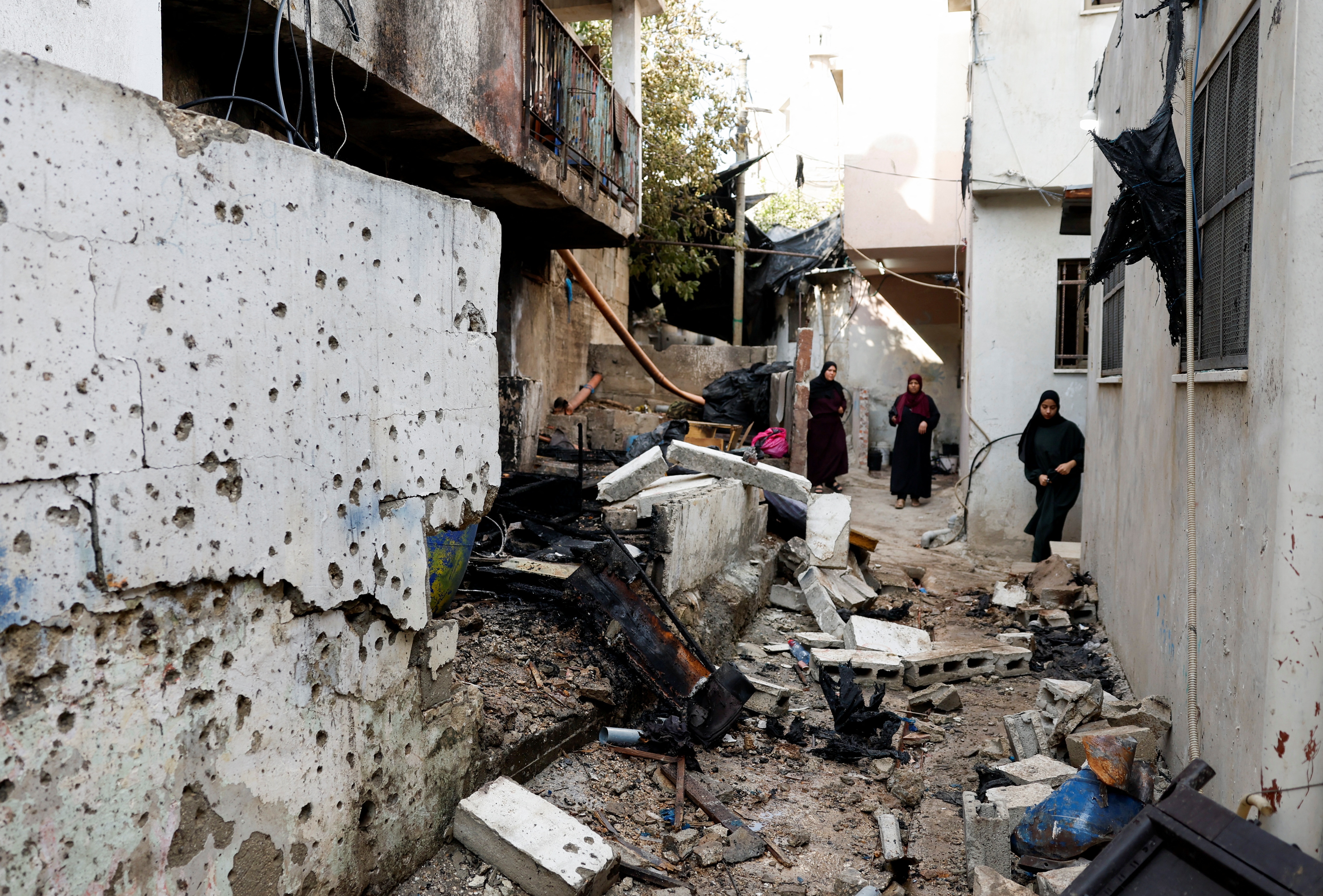 Palestinian women stand near the damaged site of a drone strike in Nur Shams refugee camp in Tulkarm in the Israeli-occupied West Bank