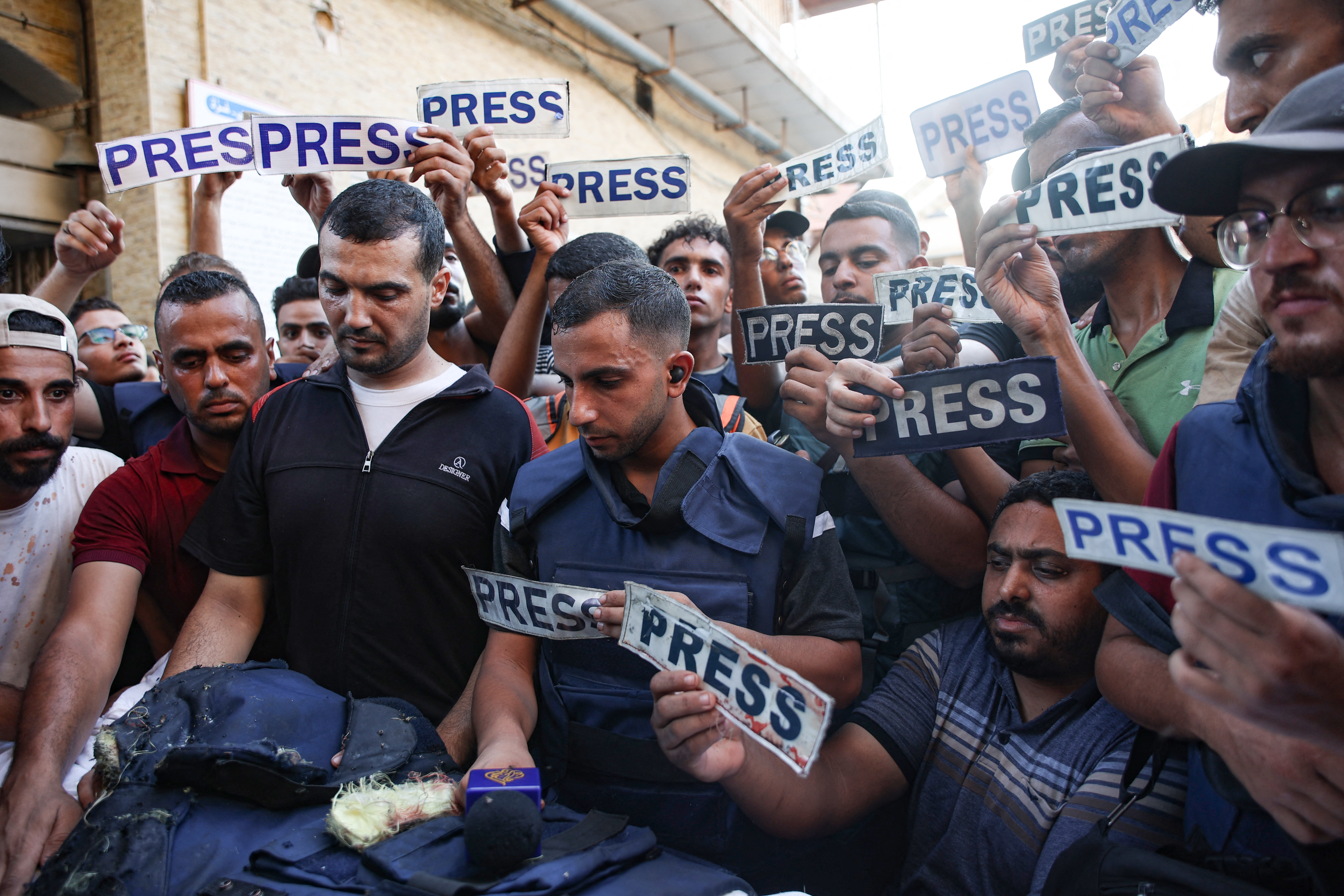Mourners and colleagues holding 'press' signs surround the body of Al-Jazeera Arabic journalist Ismail al-Ghoul, killed along with his cameraman Rami al-Refee in an Israeli strike during their coverage of Gaza's Al-Shati refugee camp, on July 31, 2024. - Al Jazeera condemned the killing of two of its journalists, calling the deaths a "cold-blooded assassination" in a statement. (Photo by Omar AL-QATTAA / AFP)