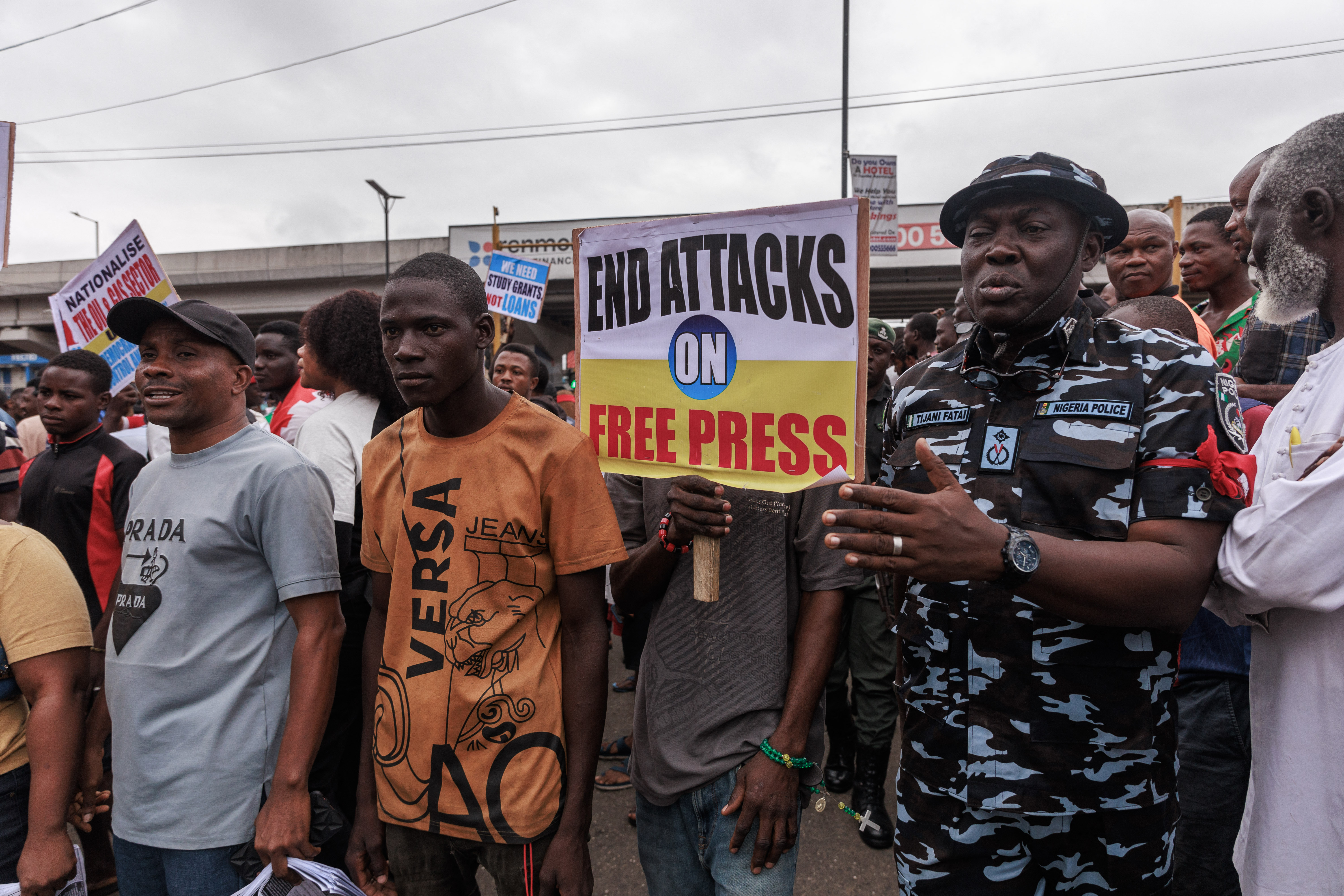 A Nigerian policeman stands next to demonstrators gathering during the End Bad Governance protest at Ikeja, Lagos