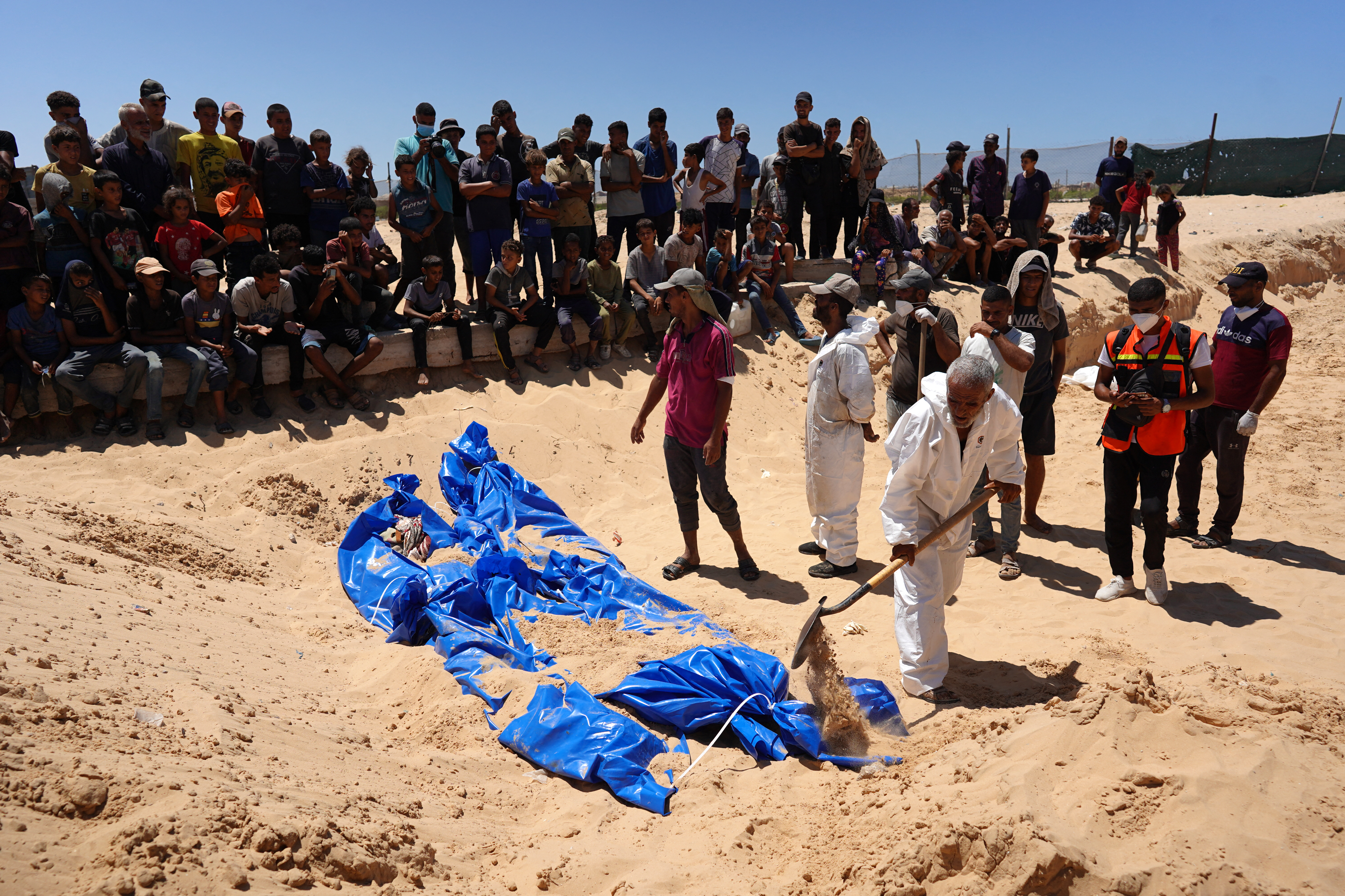 Men burry bodies that were taken and later released by Israel during a mass funeral at a cemetery in Khan Yunis in the southern Gaza Strip on August 5, 2024, amid the ongoing conflict between Israel and the Palestinian Hamas militant group. (Photo by Bashar TALEB / AFP)