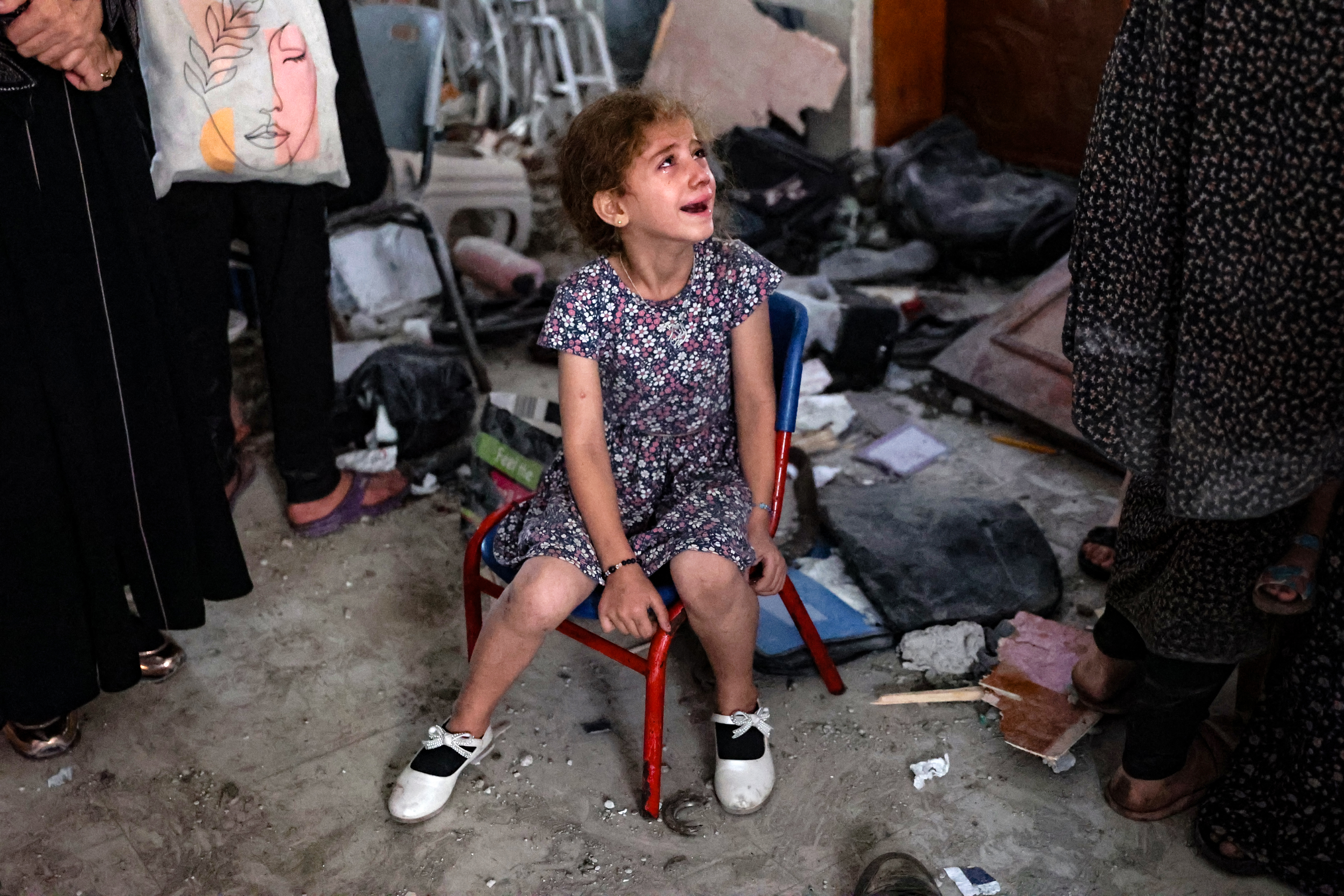 A young girl cries inside a school used as a temporary shelter for displaced Palestinians in Gaza City, following an Israeli strike