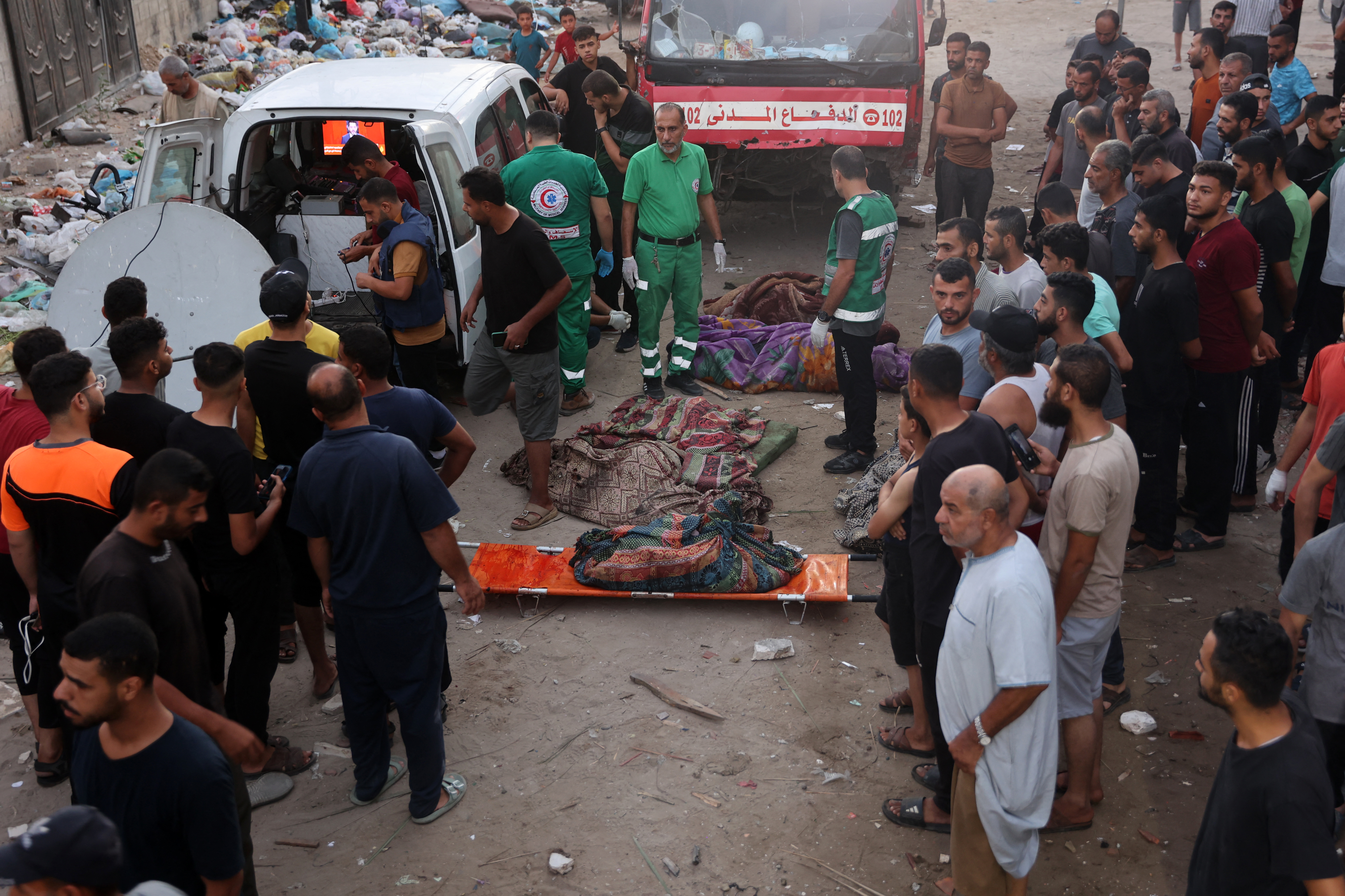 Displaced Palestinians watch as first responders prepare to transport corpses of people killed in an Israeli strike on a school in Gaza City on August 10, 2024, that killed more than 90 people. (Photo by Omar AL-QATTAA / AFP)