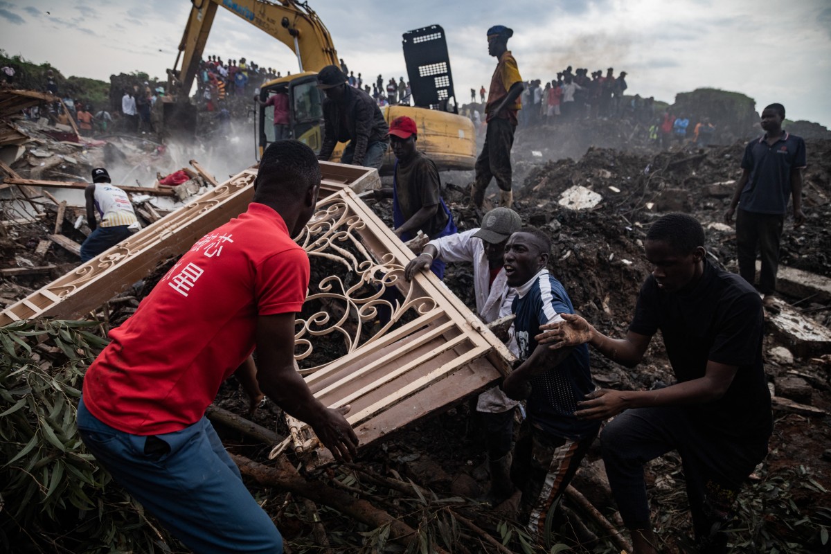 Men fight for a metallic door from the debris of a house hit by a landfill collapse in Kampala on August 10, 2024. - Eight people including two children were killed when mountains of garbage collapsed at a landfill in the Ugandan capital Kampala on August 10, the city authority said. (Photo by BADRU KATUMBA / AFP)