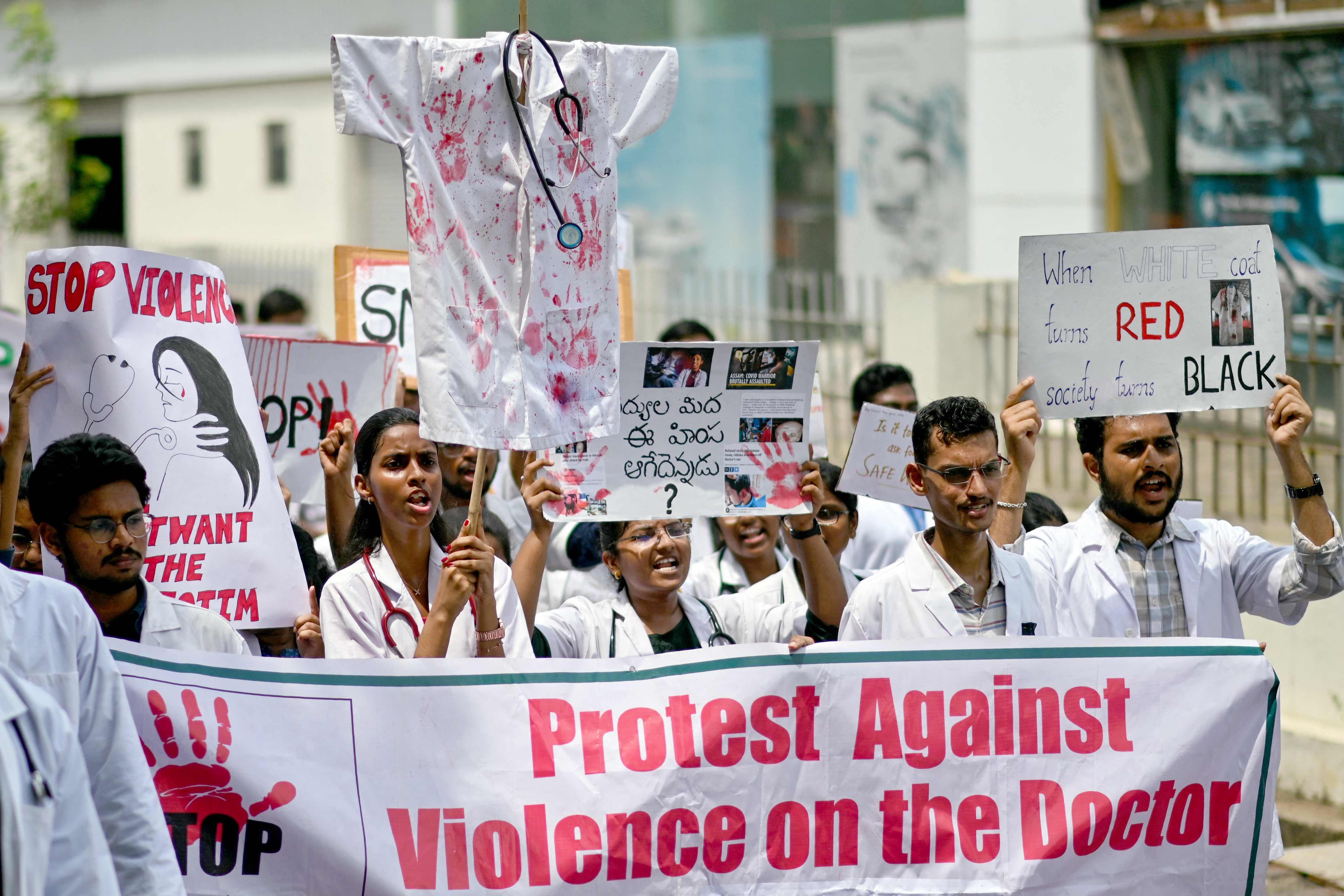 Doctors hold posters to protest the rape and murder of a young medic from Kolkata, at the Government General Hospital in Vijayawada on August 14