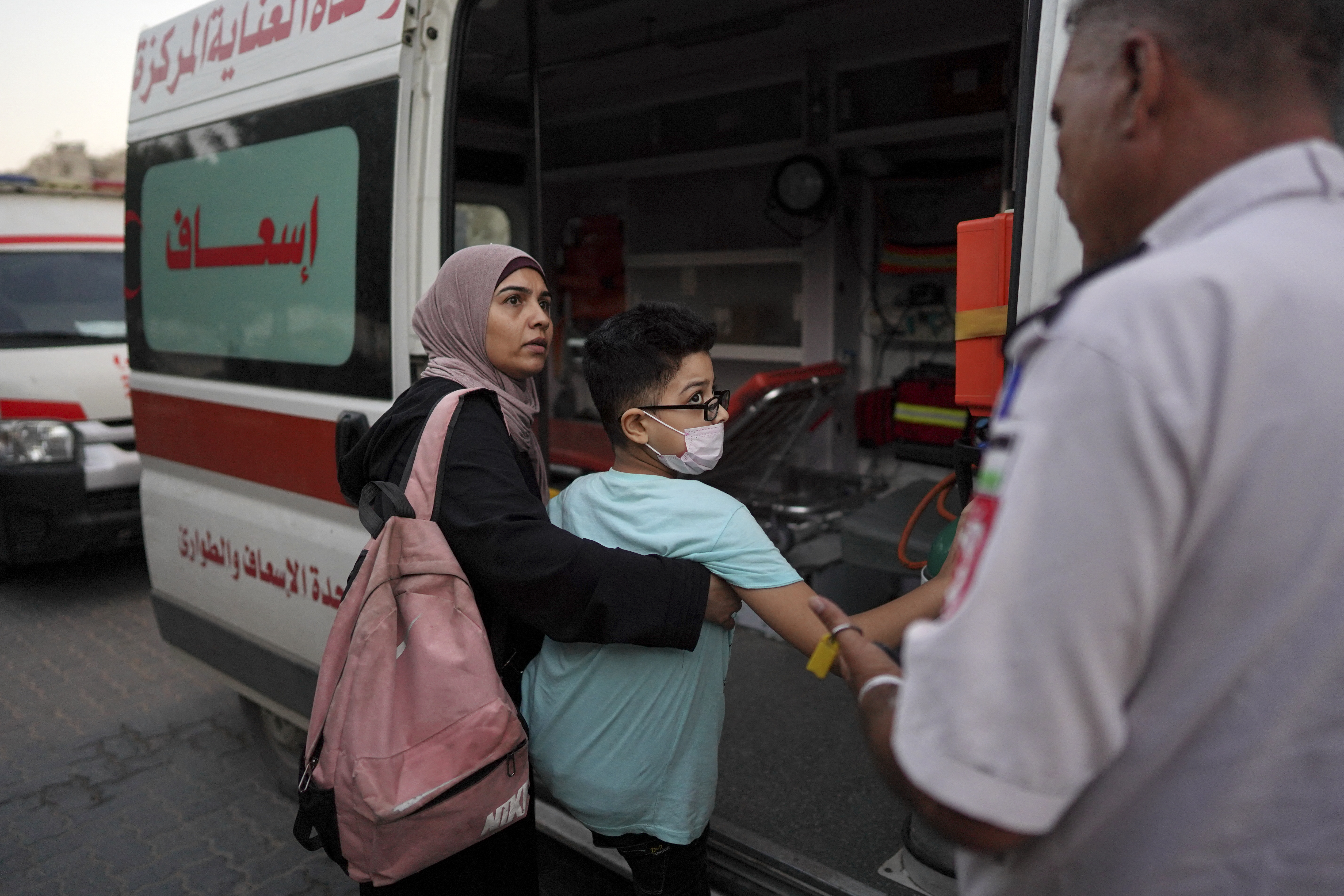 A woman helps a relative get in an ambulance at Al-Nasser hospital in Khan Yunis on August 15, 2024, after permission from the Israeli authorities was given for 11 children suffering from cancer to leave Gaza through the Kerem Shalom crossing