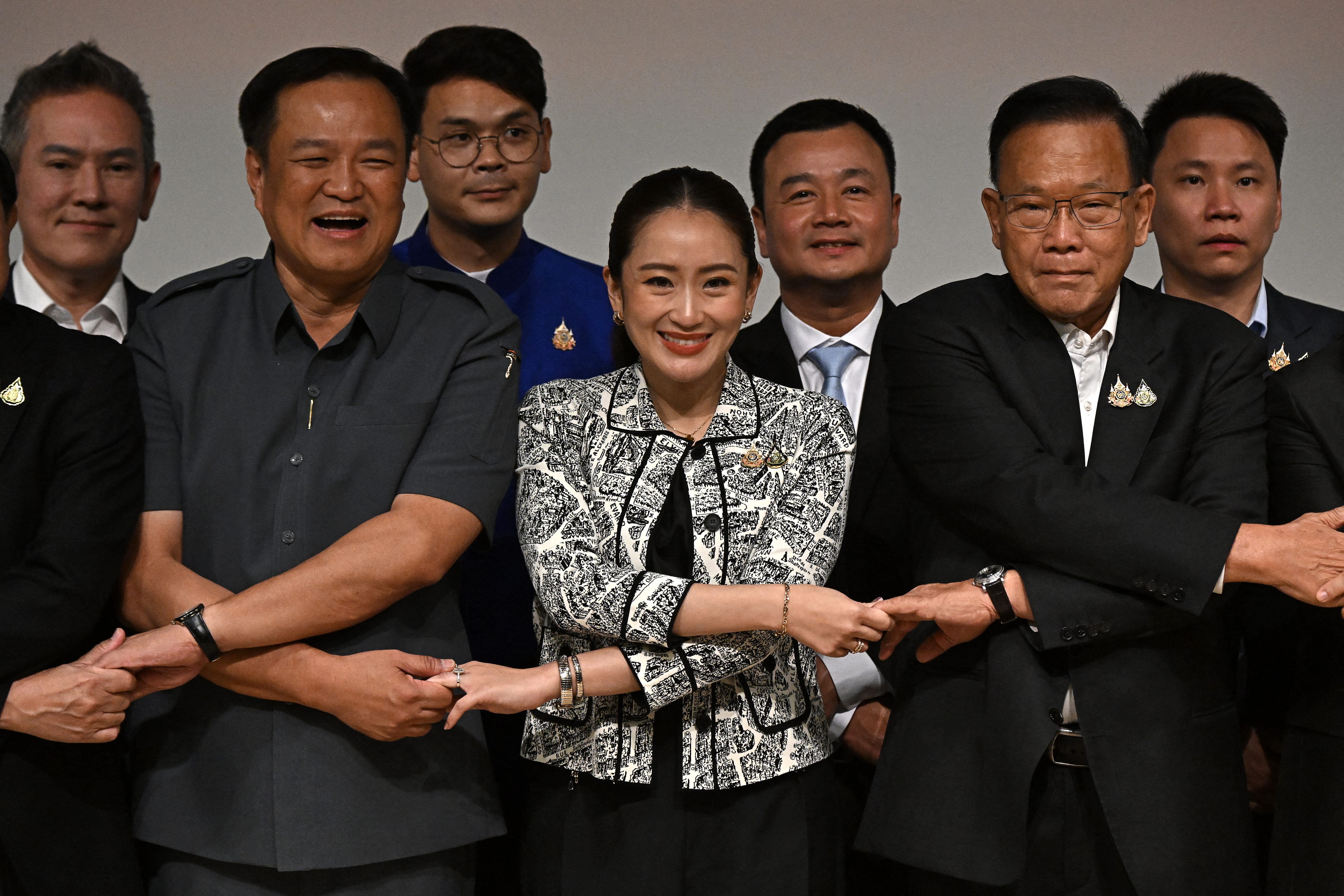 Paetongtarn Shinawatra with members of the ruling coalition. They are locking arms.