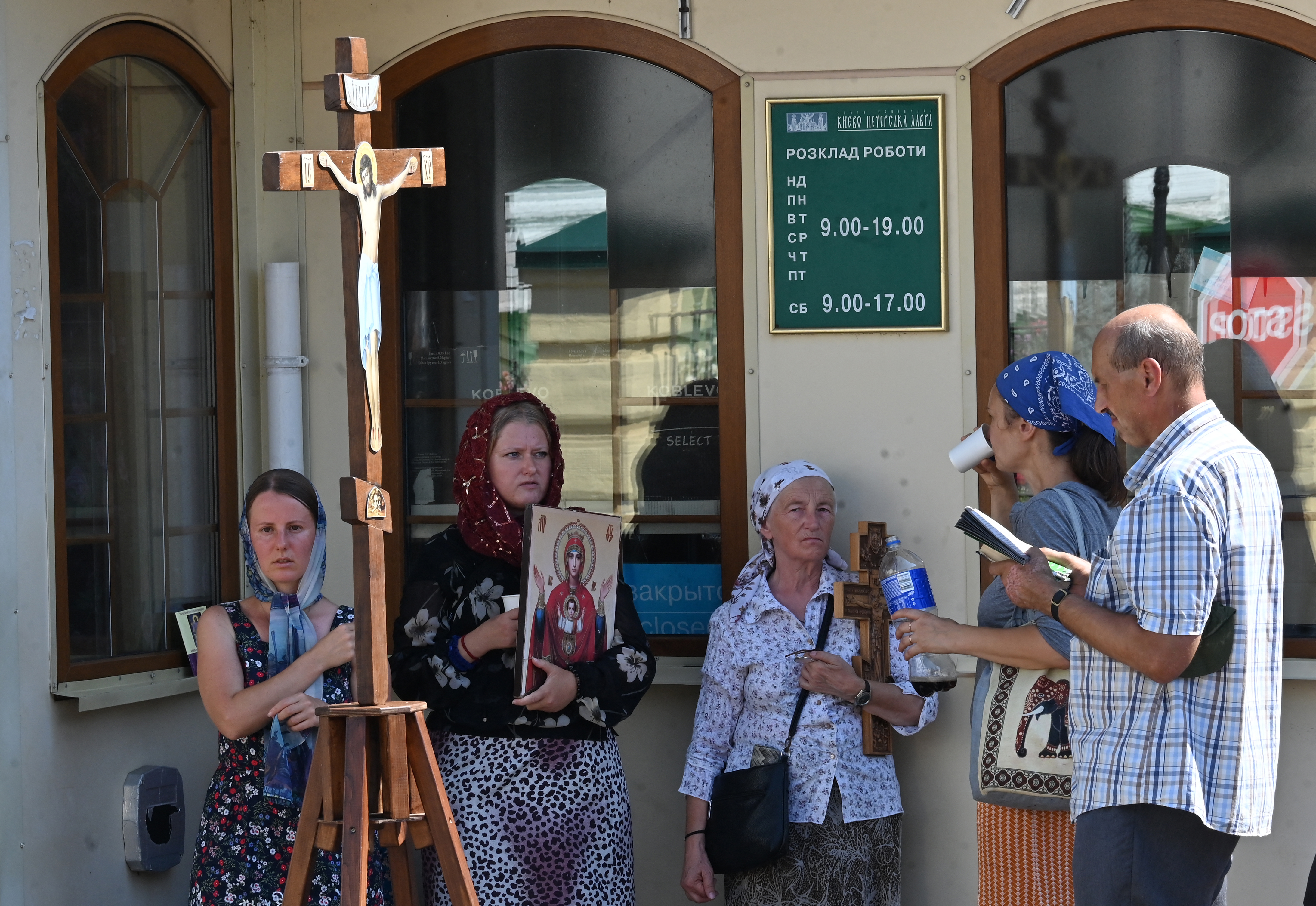 A handful of UOC followers pray outside the Kyiv Pechersk Lavra. They are holding icons and prayer books.