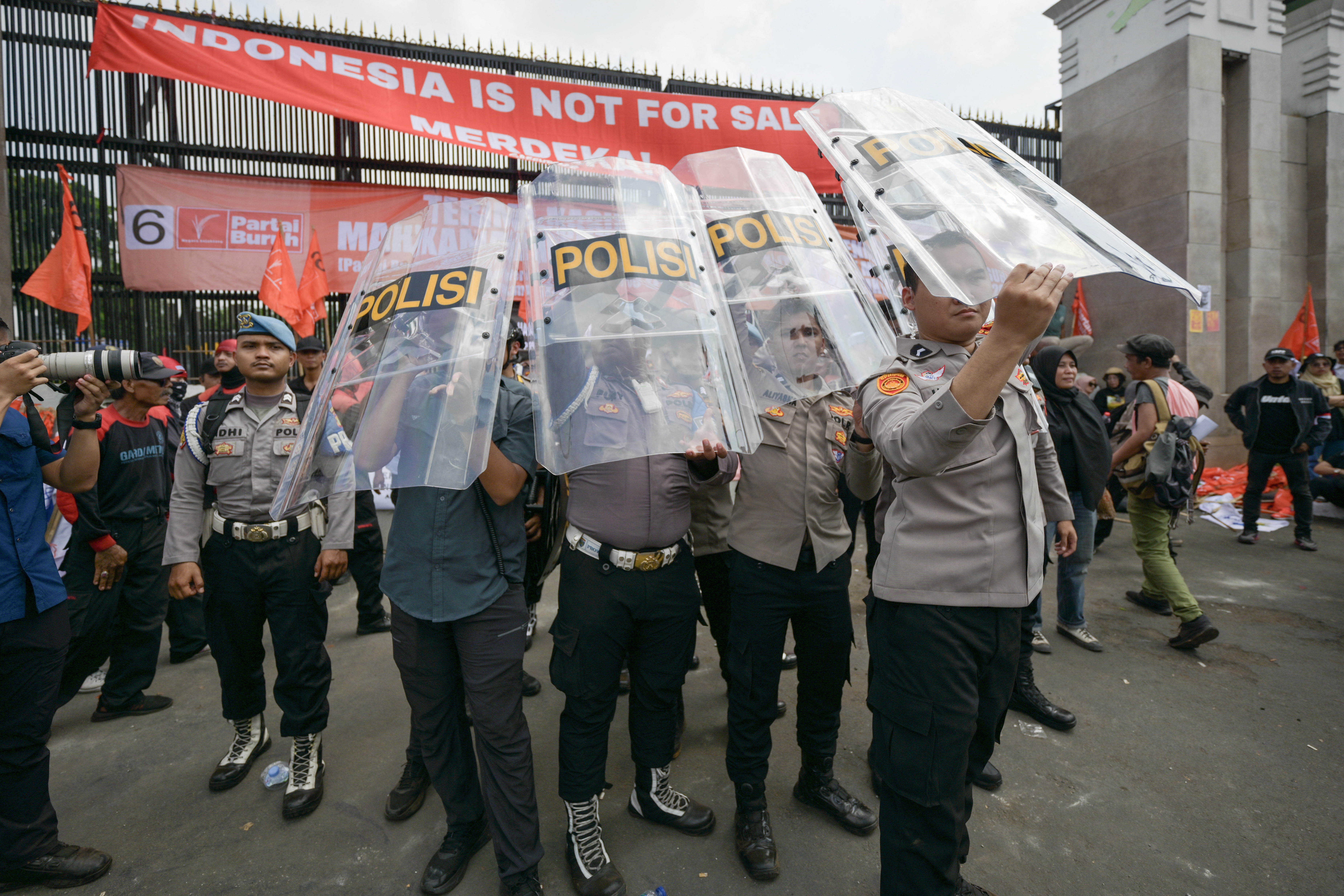 People attend a protest outside the Indonesian Parliament against the revisions to the country's election law