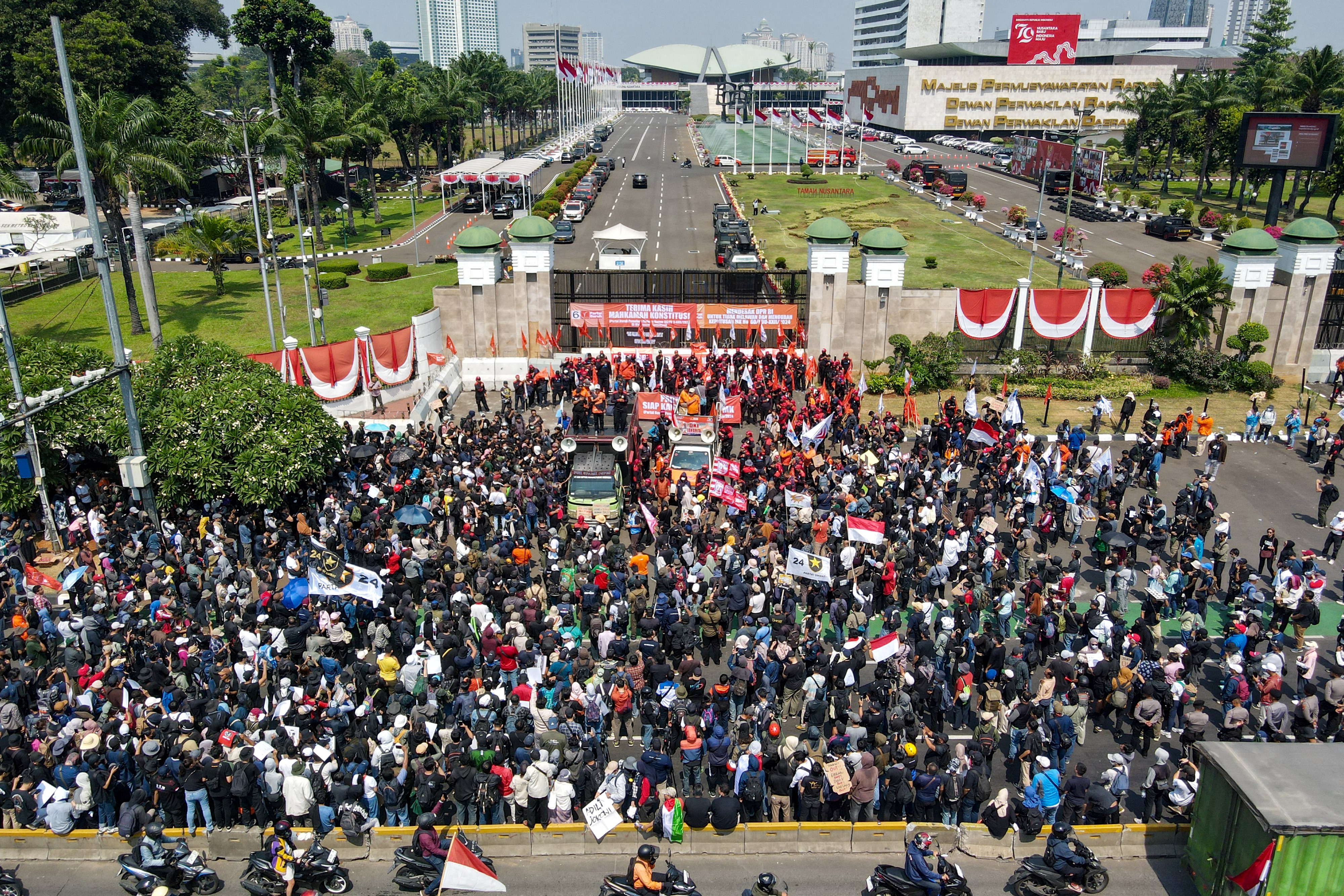 People attend a protest outside the Indonesian Parliament against the revisions to the country's election law