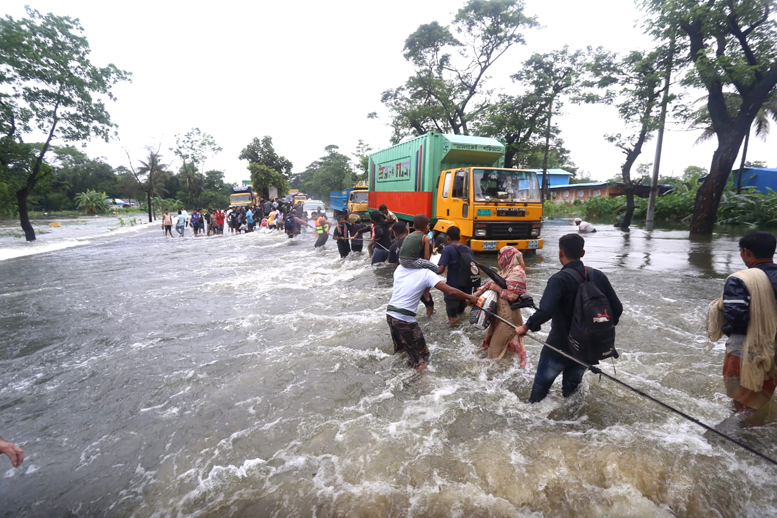 People wade through flood waters in Feni