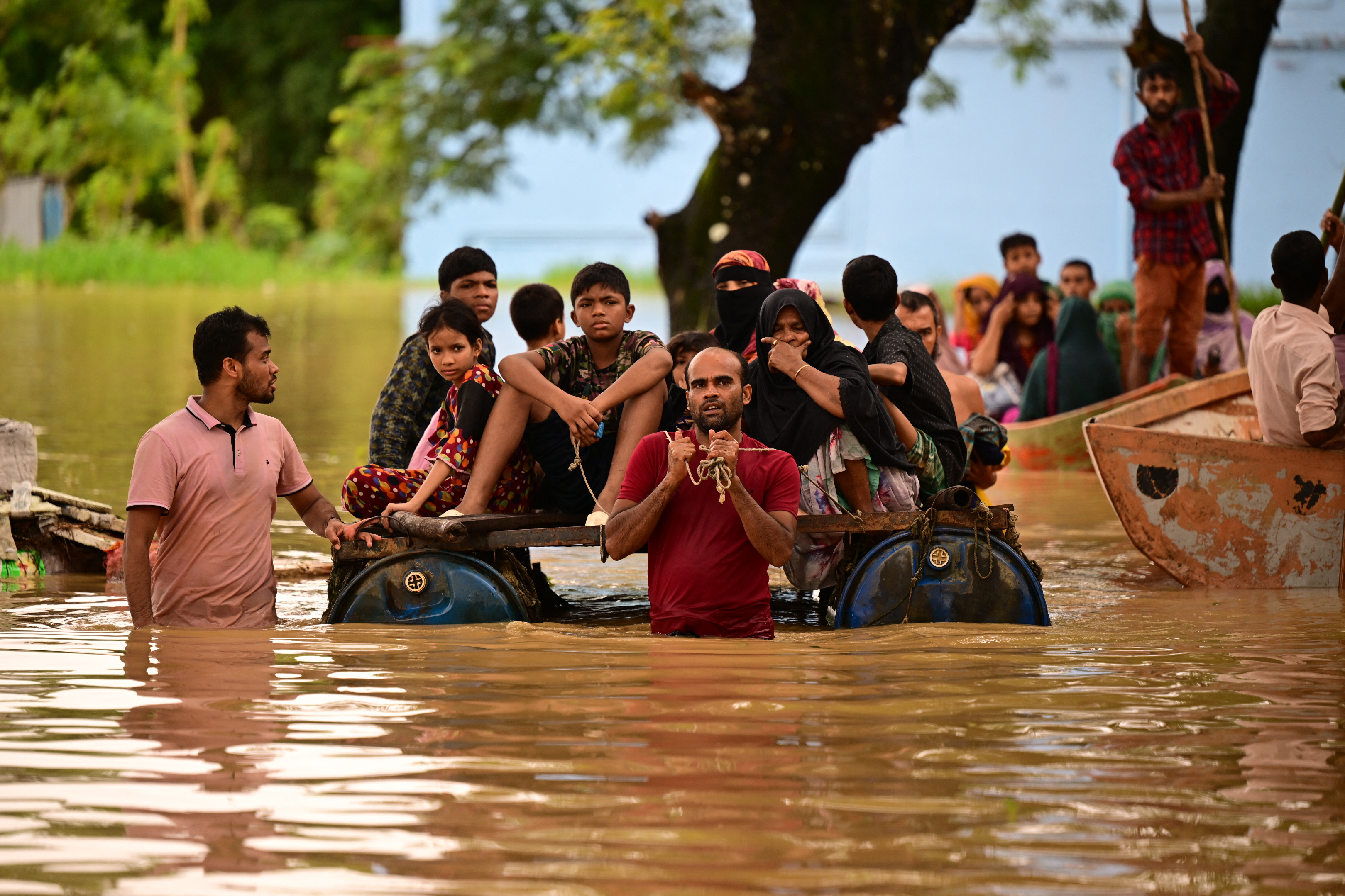 People wade through flood waters in Feni