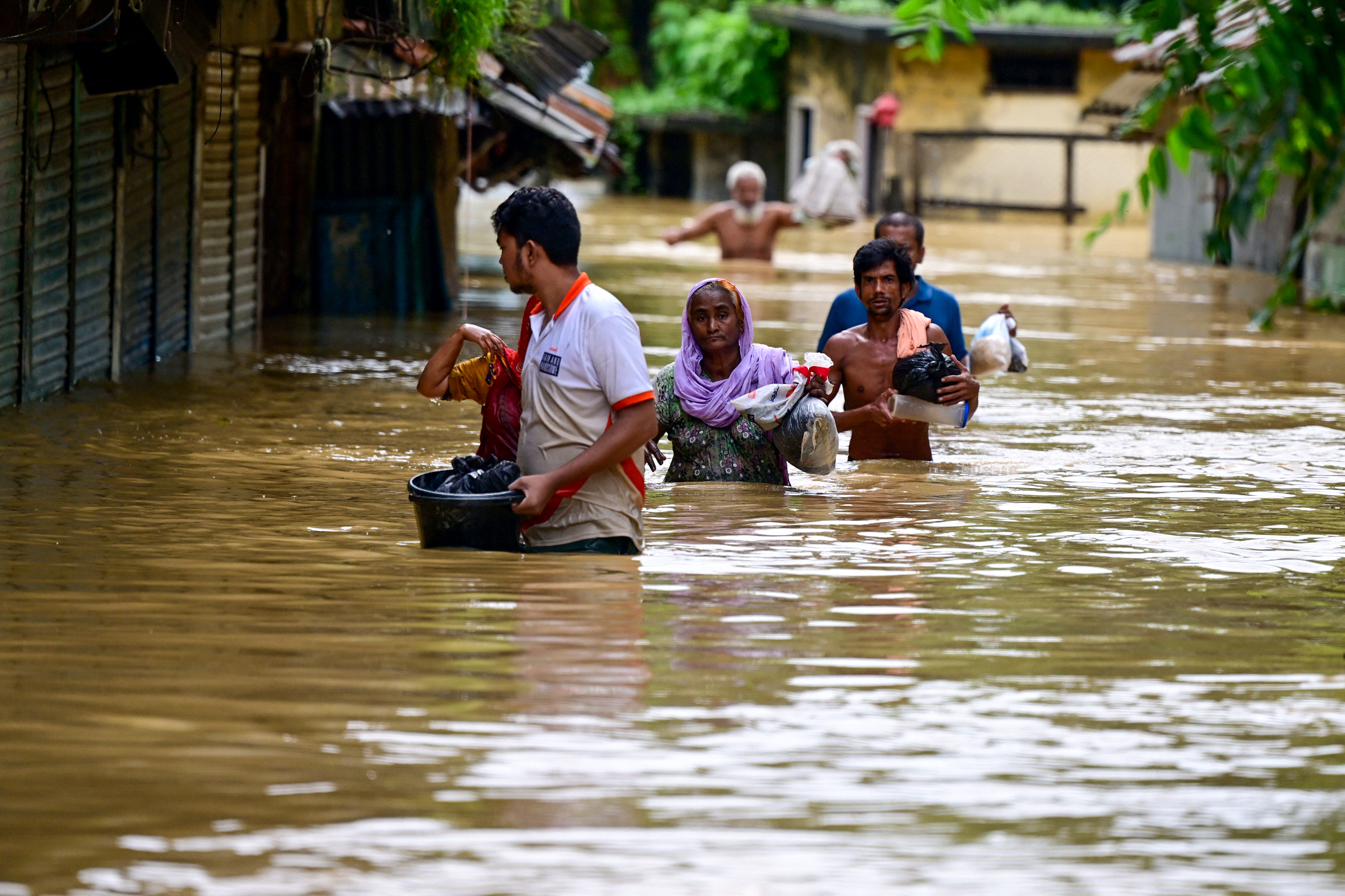 People wade through flood waters in Feni