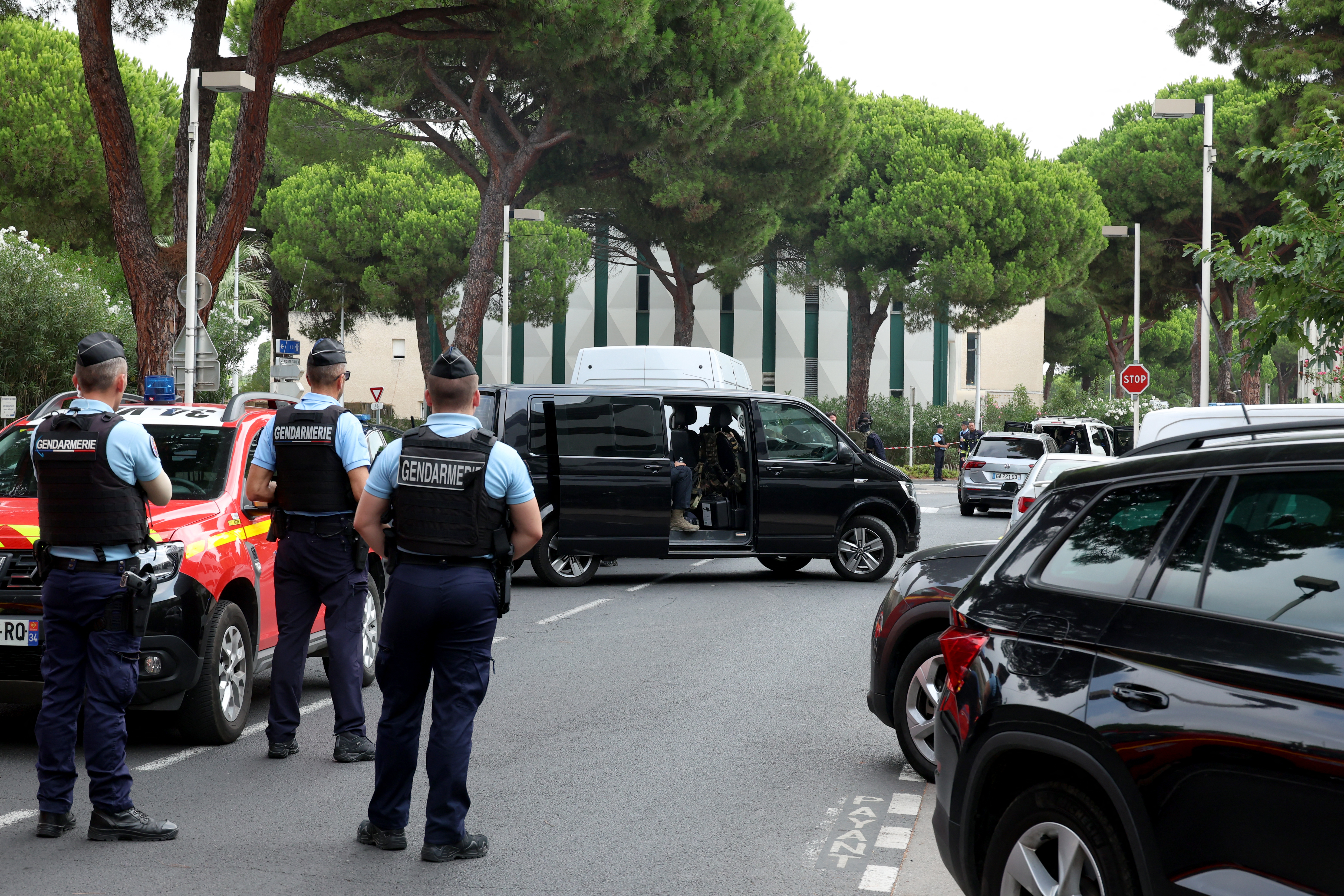 Law enforcement officers stand in front of a synagogue, in background on the right on the photo, following the fire and explosion of cars in La Grande-Motte, south of France, on August 24, 2024. - At least two cars, one containing a gas bottle, were set alight on the morning of August 24, 2024, in front of the synagogue in La Grande-Motte, causing an explosion that injured a local policeman, the French gendarmerie and the town's mayor said. (Photo by Pascal GUYOT / AFP)