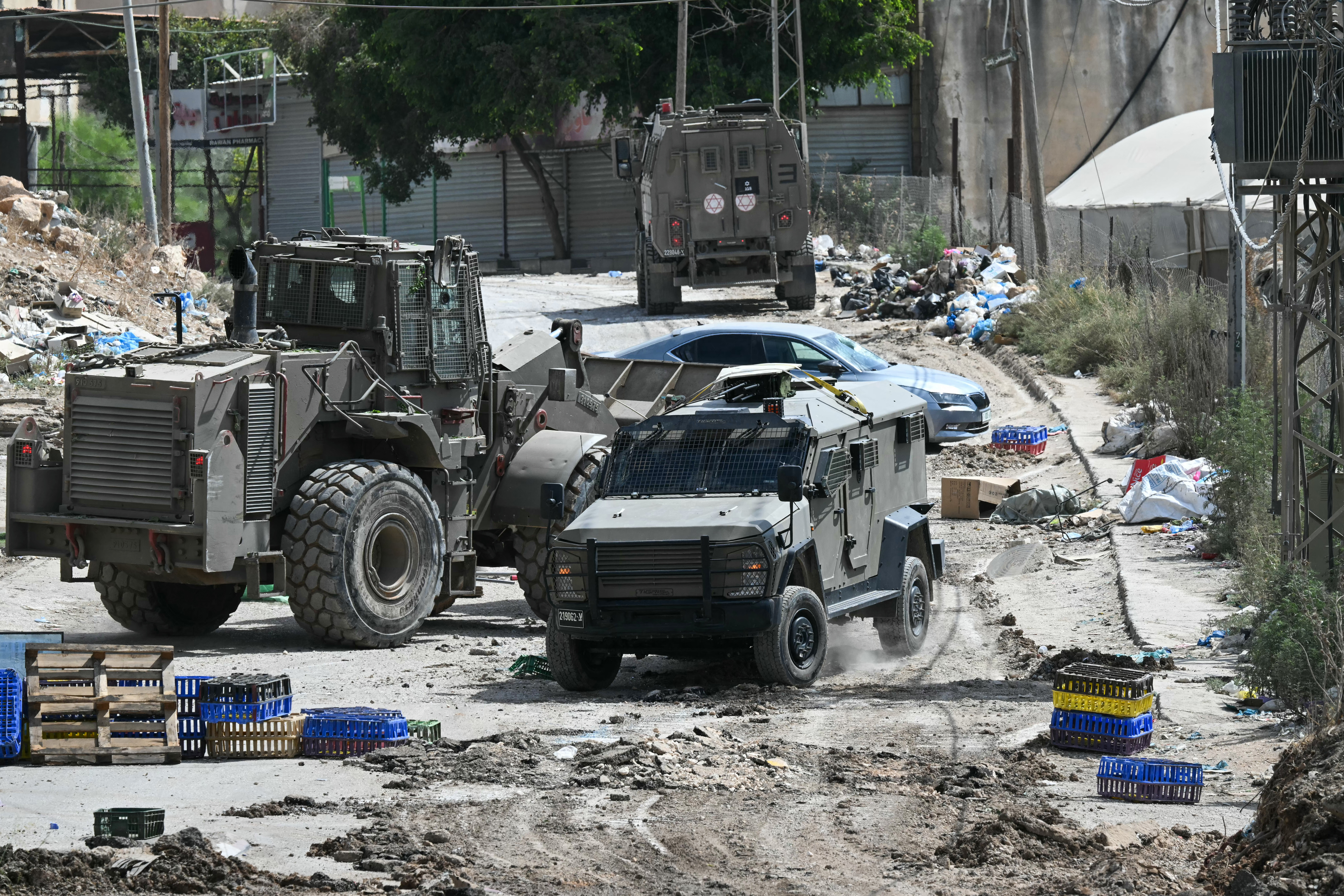 Israeli military armoured vehicles including a bulldozer block a road during a raid in the al-Faraa camp for Palestinian refugees