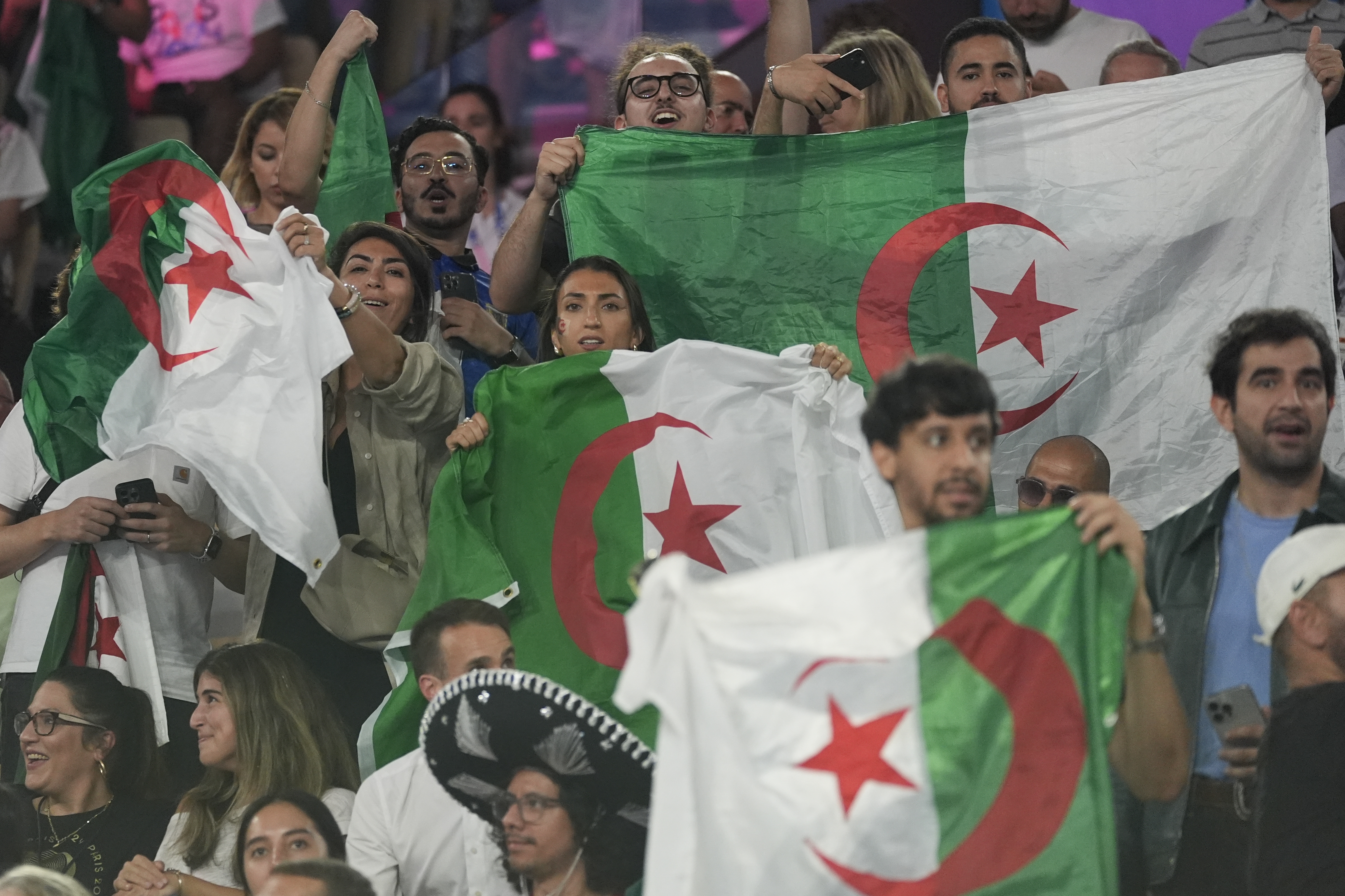 Algeria fans cheer as Algeria's Imane Khelif prepares to fight China's Yang Liu in their women's 66 kg final boxing match at the 2024 Summer Olympics, Friday, Aug. 9, 2024, in Paris, France. (AP Photo/Ariana Cubillos)