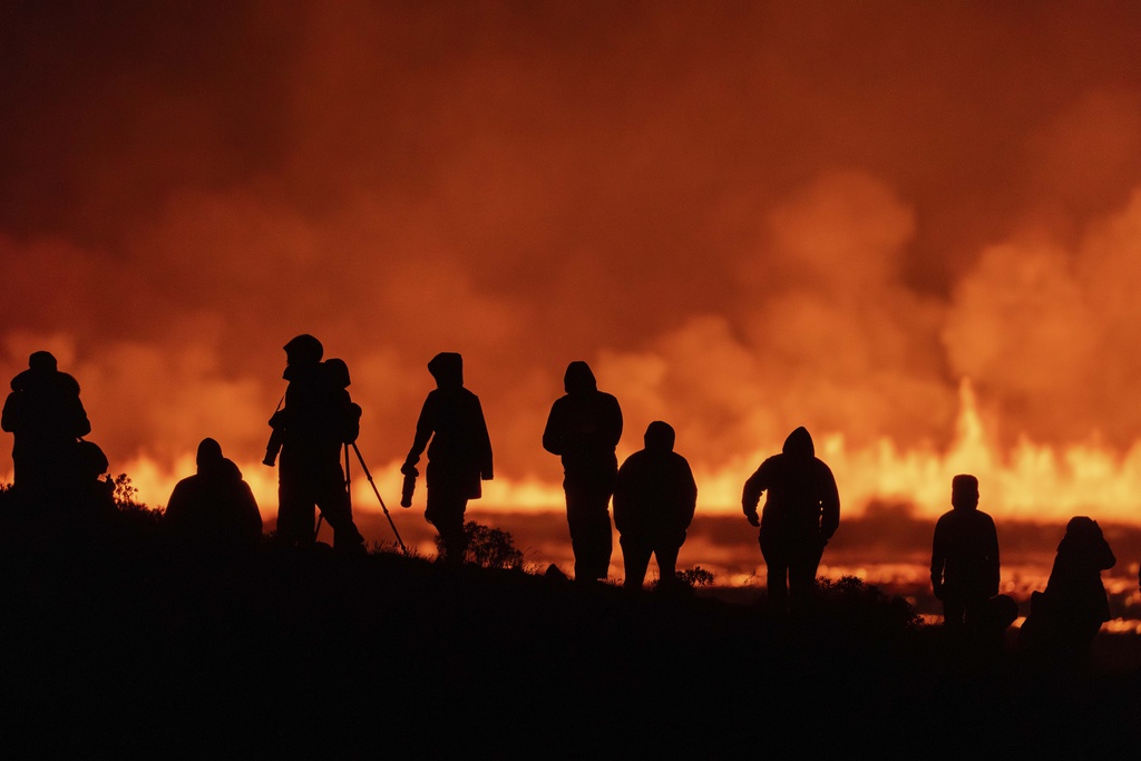 Tourists and visitors try to get a view of a volcano in southwestern Iceland, which erupted for the sixth time since December, spewing red lava through a new fissure on the Reykjanes Peninsula, on August 22 [Marco di Marco/AP Photo]