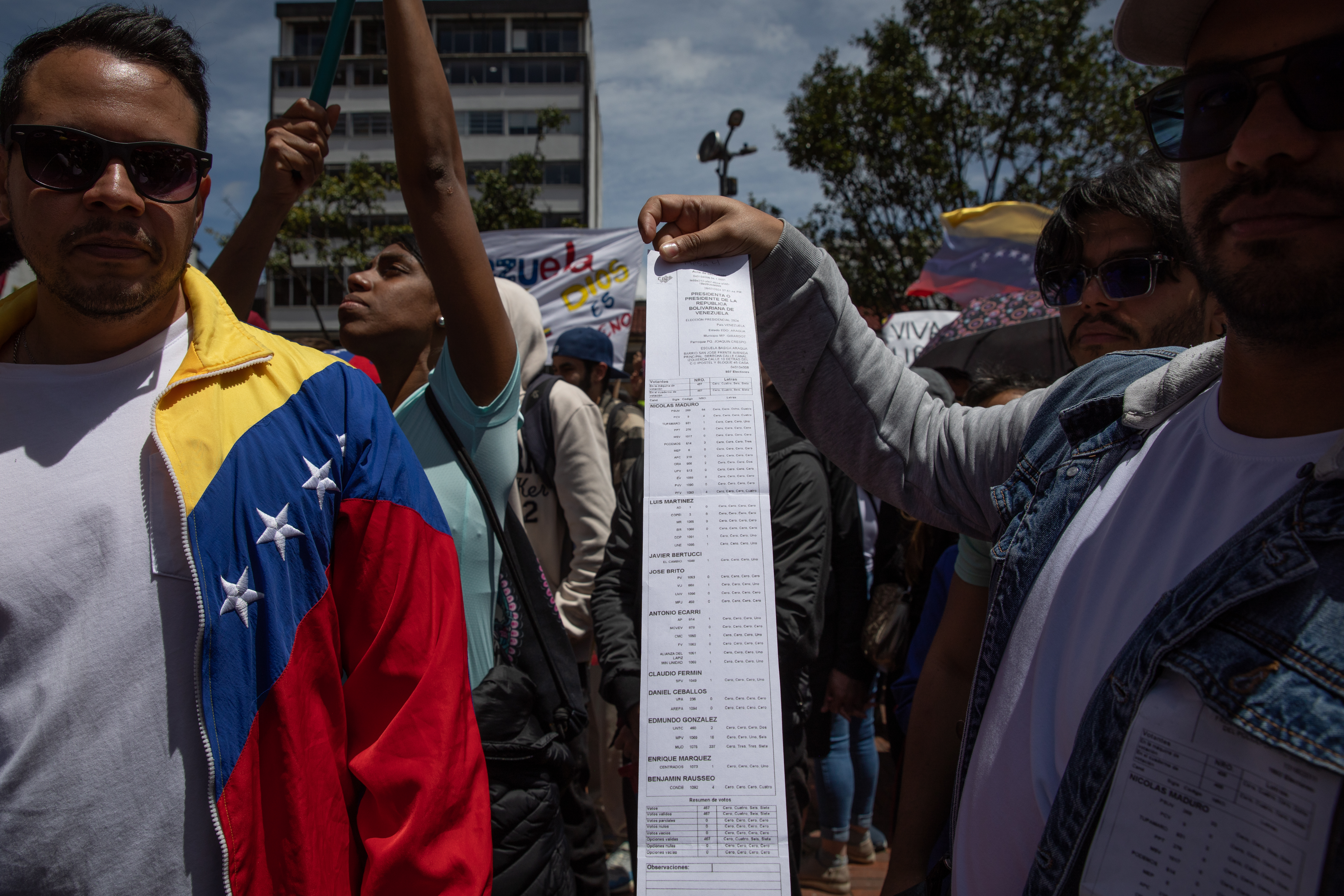 A protester in Bogota shows a print-out of the voter tallies released by the Venezuelan opposition. The sheet is long and narrow, and is printed with tight rows of names.