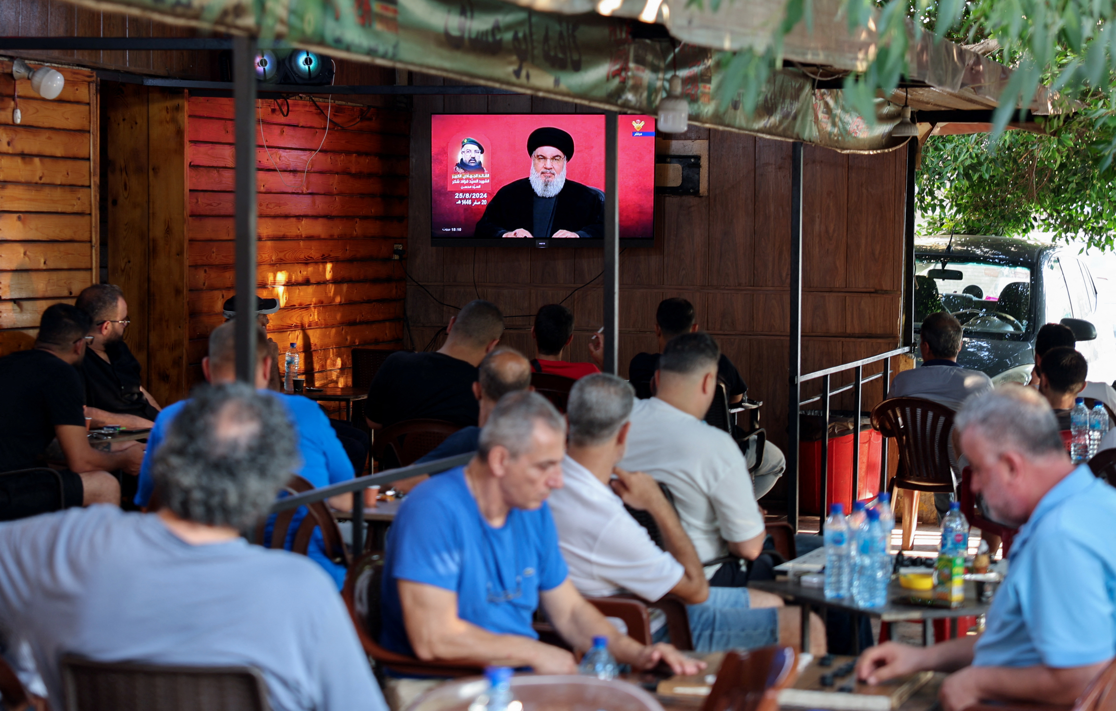 People watch Lebanon's Hezbollah leader Sayyed Hassan Nasrallah delivering a televised address, as they sit at a cafe in Beirut, Lebanon August 25, 2024. [REUTERS/Mohamed Azakir