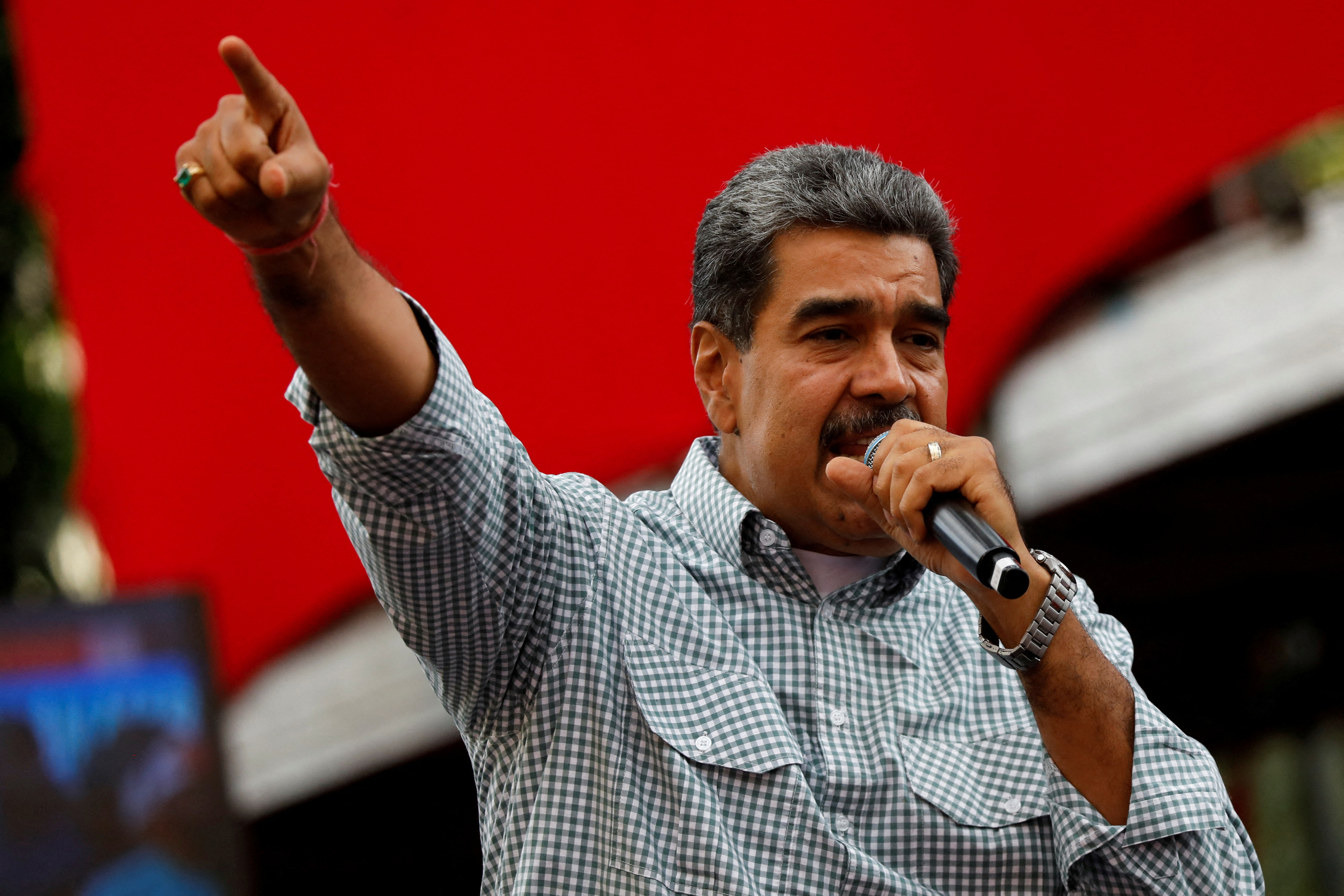 Nicolas Maduro speaks into a microphone and points in gesture.