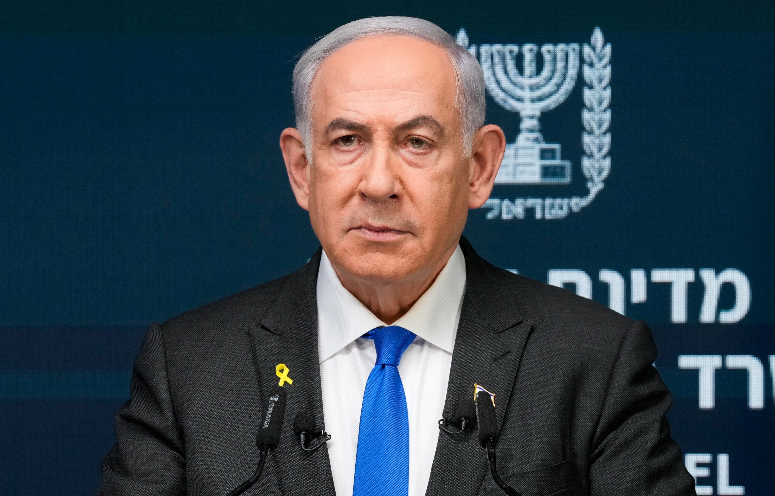 Benjamin Netanyahu at a lectern. He looks stern. An Israeli flag is behind him