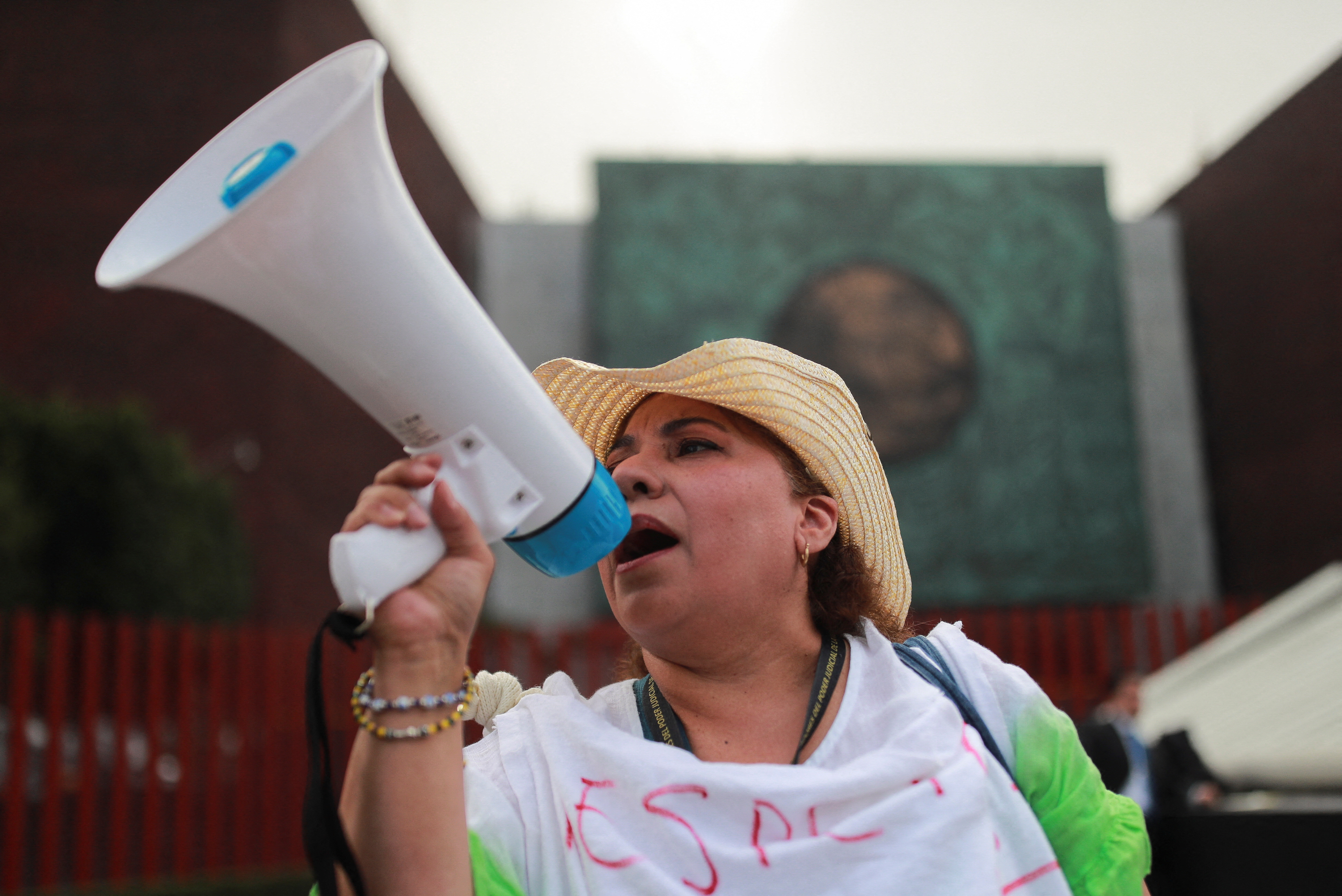 A female protester in a straw hat speaks through a megaphone in Mexico City.