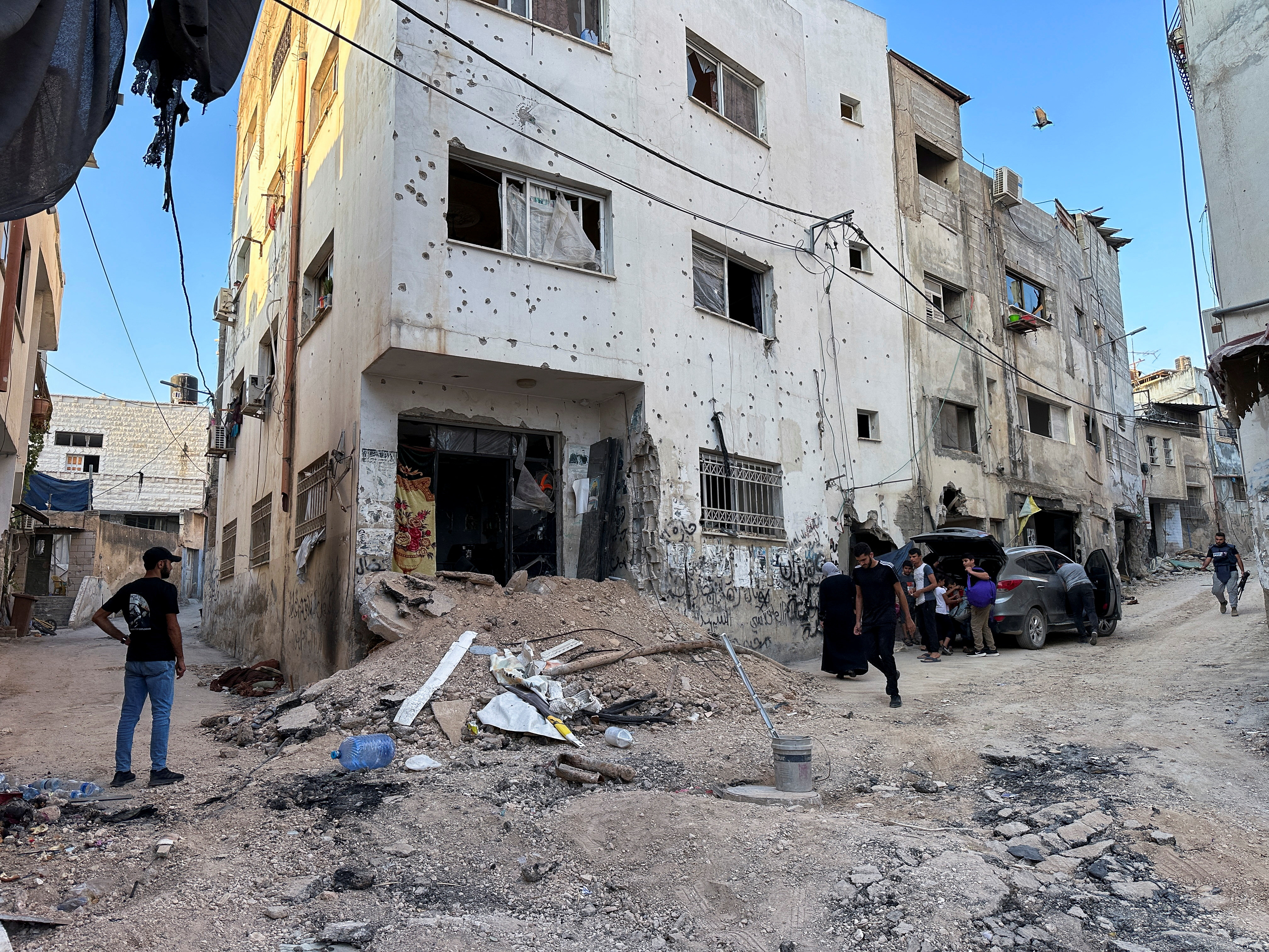 Palestinians assess damage in the street following an Israeli military operation in Jenin