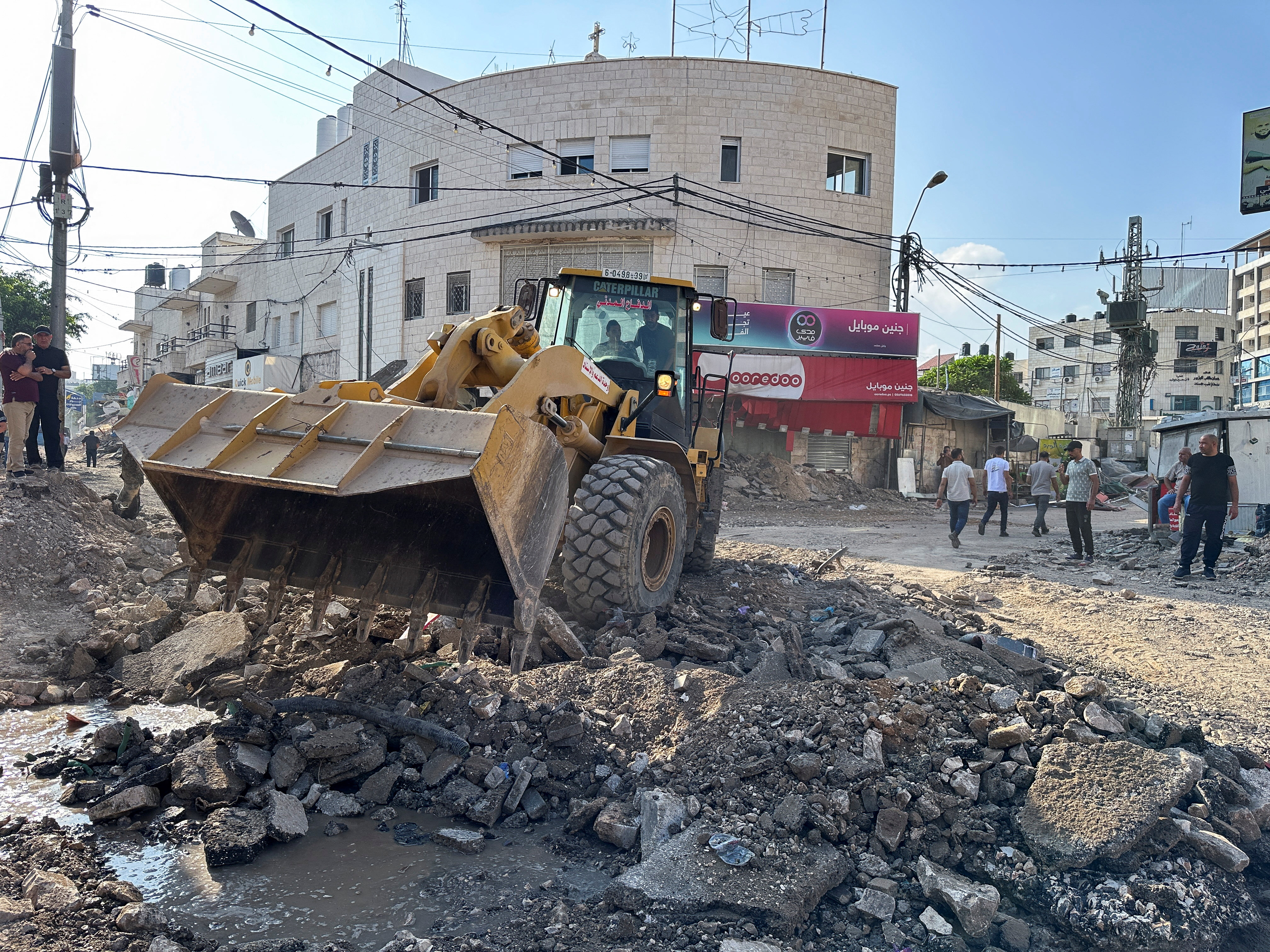 Palestinians assess damage in the street following an Israeli military operation in Jenin