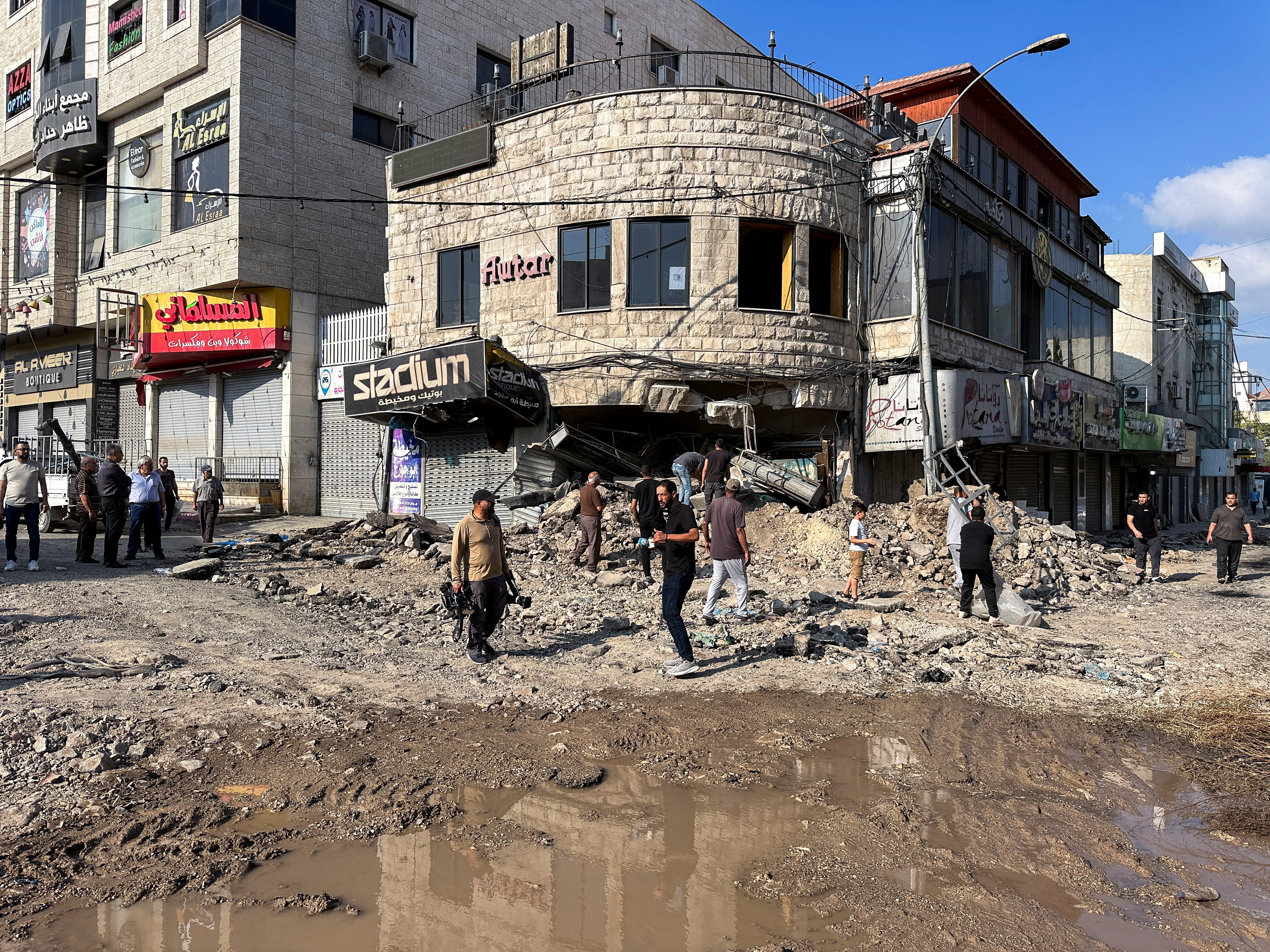 Palestinians assess damage in the street following an Israeli military operation in Jenin