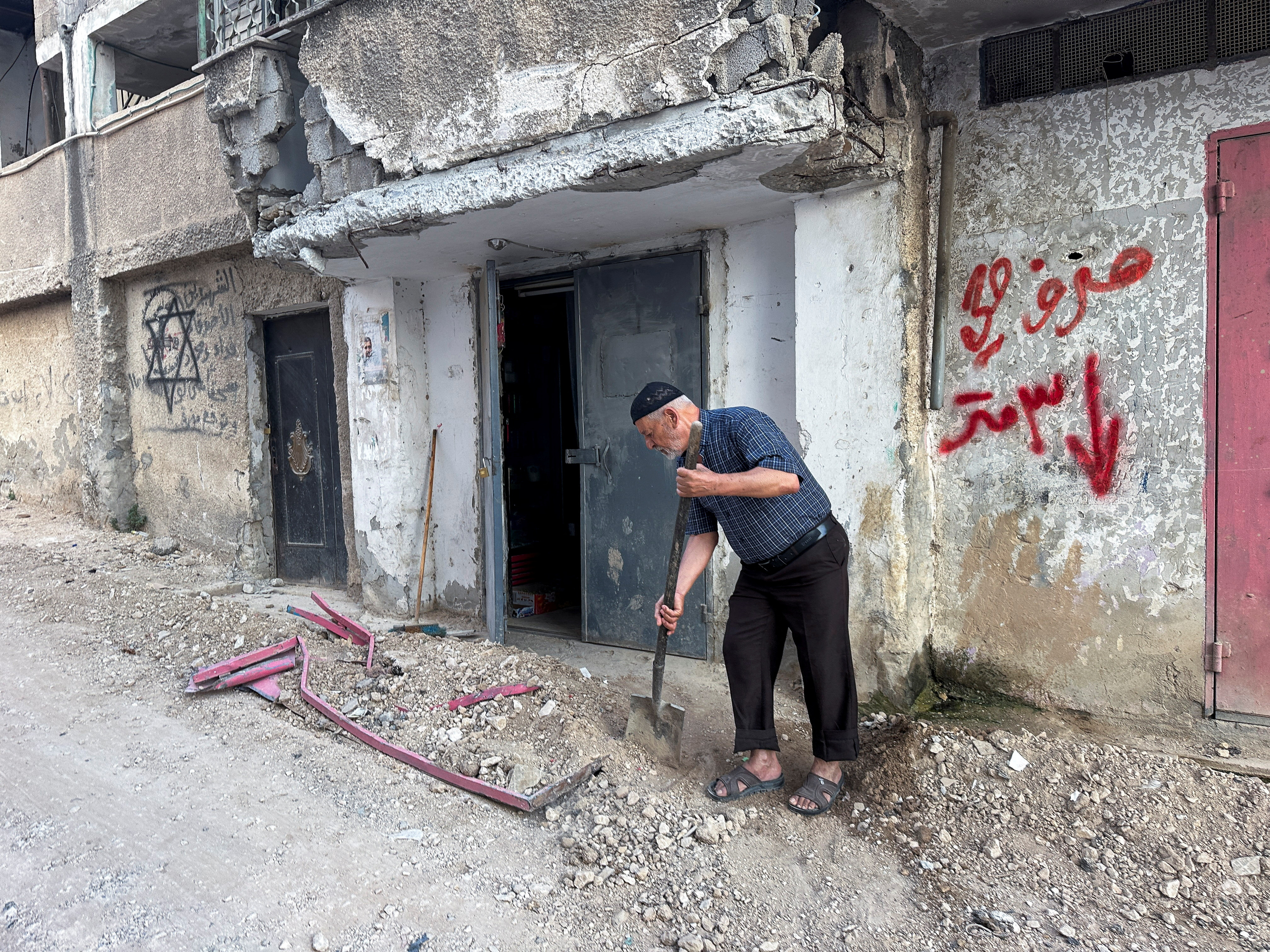 Palestinians assess damage in the street following an Israeli military operation in Jenin