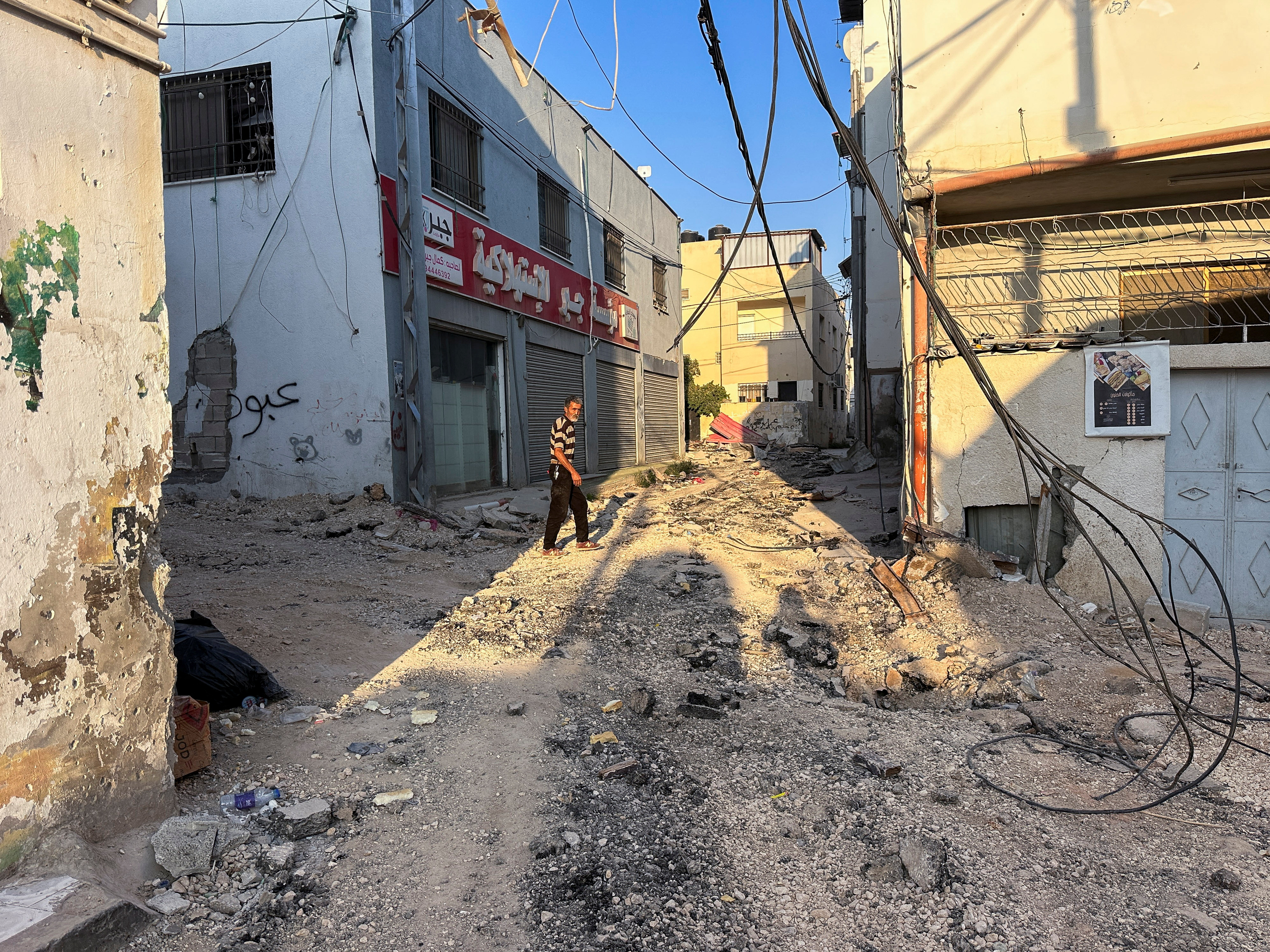Palestinians assess damage in the street following an Israeli military operation in Jenin