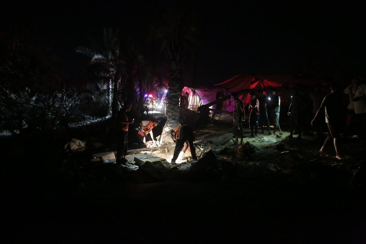 people look through a destroyed tent camp at night