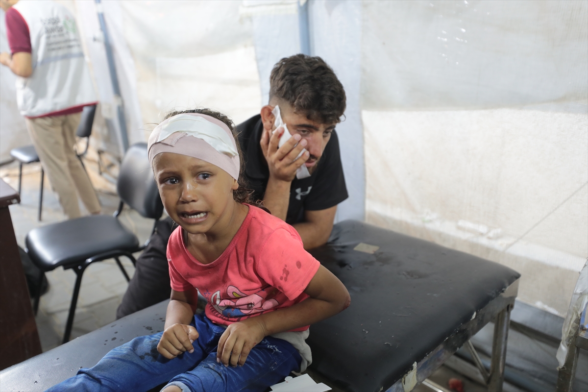 a little fill in a pink shirt with a bandage on her head in a tent hospital