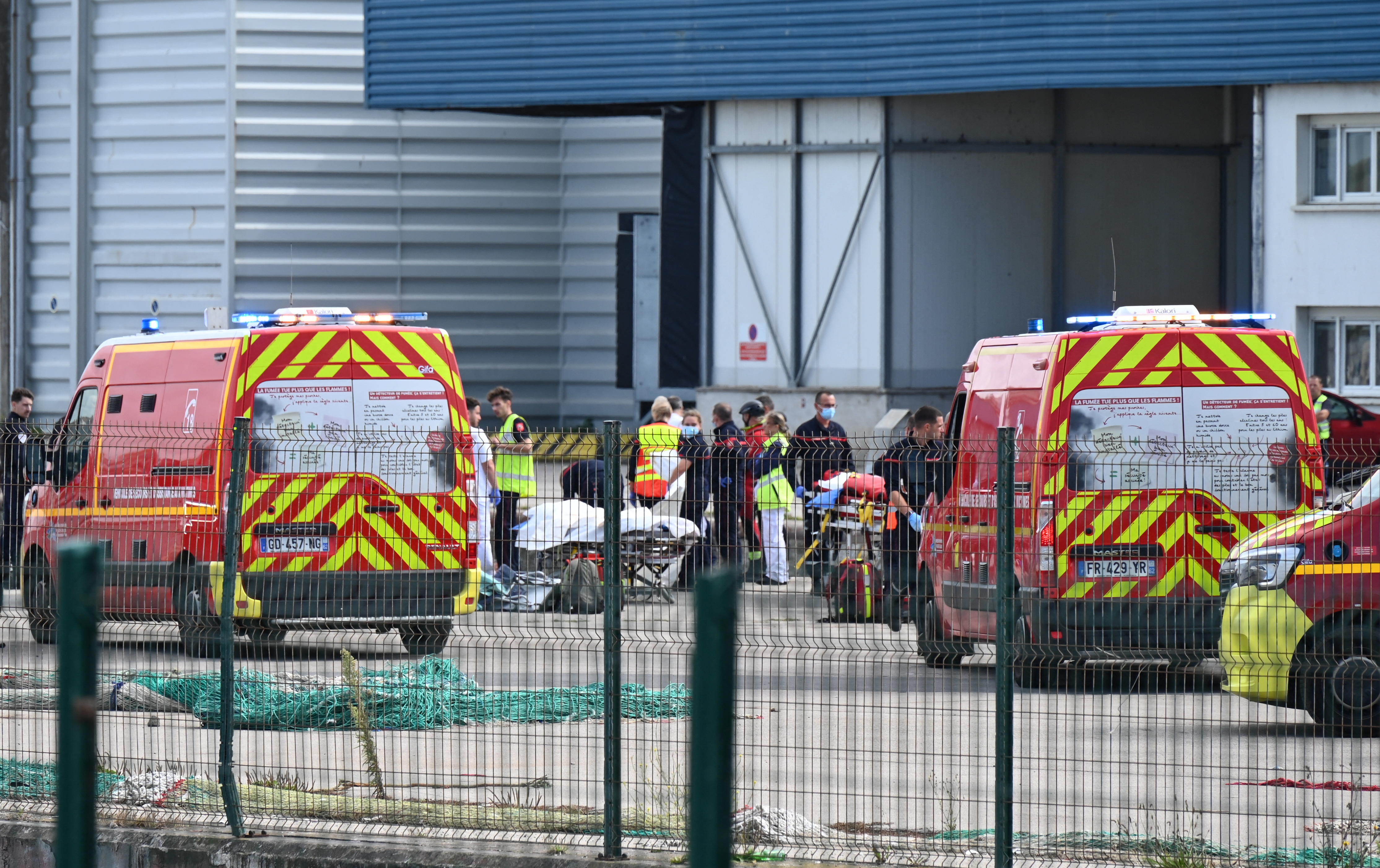 Firefighters handle the bodies of migrants who died trying to cross the English Channel