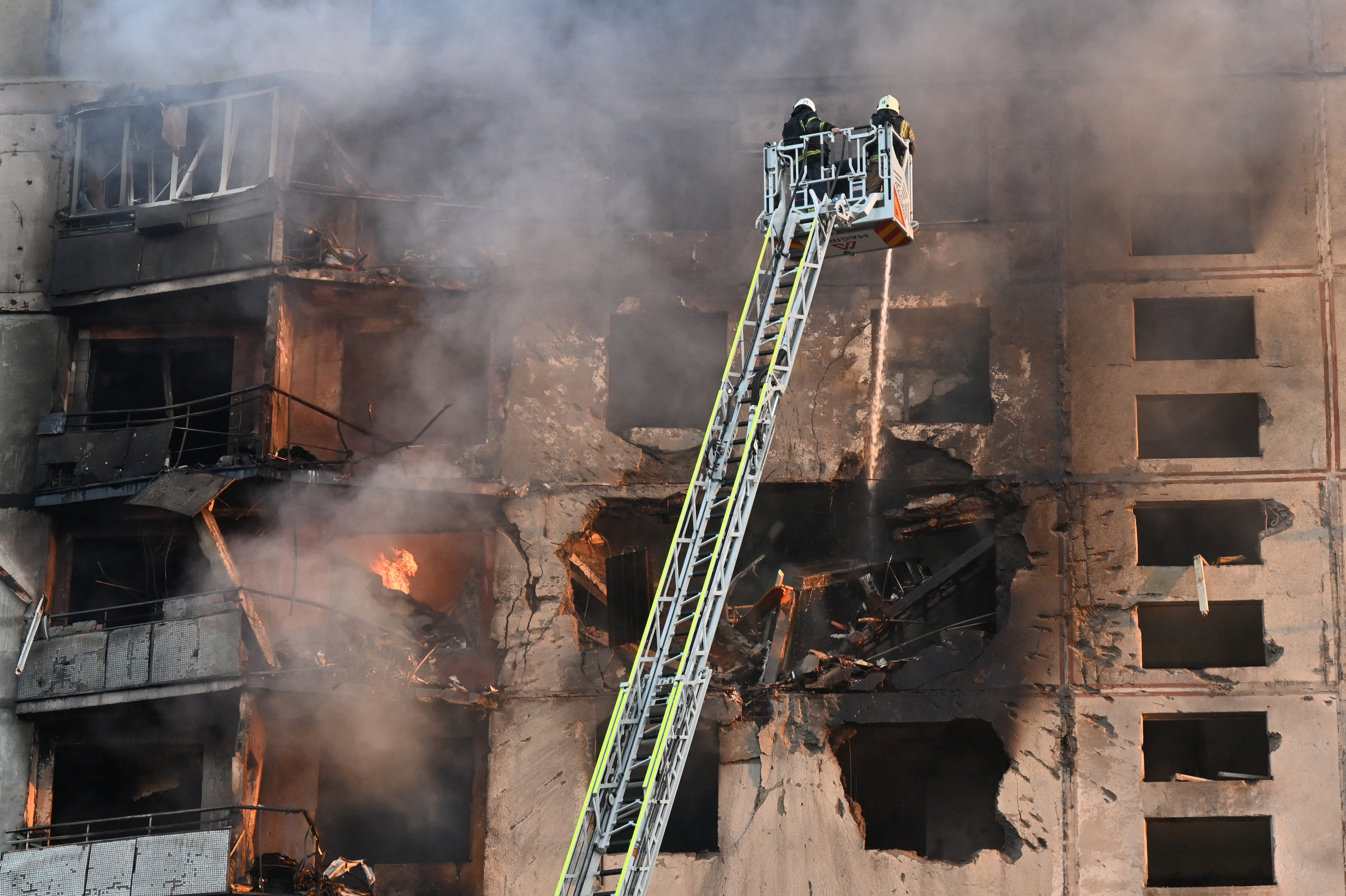 Ukrainian rescuers work to extinguish a fire in a residential building following a missile attack in Kharkiv