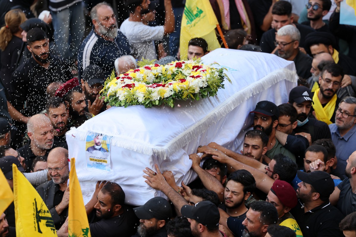 Mourners toss rice over the coffin of person a killed after hundreds of paging devices exploded in a deadly wave across Lebanon the previous day, during a funeral procession in Beirut's southern suburbs on September 18, 2024. - Hundreds of pagers used by Hezbollah members exploded across Lebanon on September 17, killing at least nine people and wounding around 2,800 in blasts the Iran-backed militant group blamed on Israel. (Photo by ANWAR AMRO / AFP)