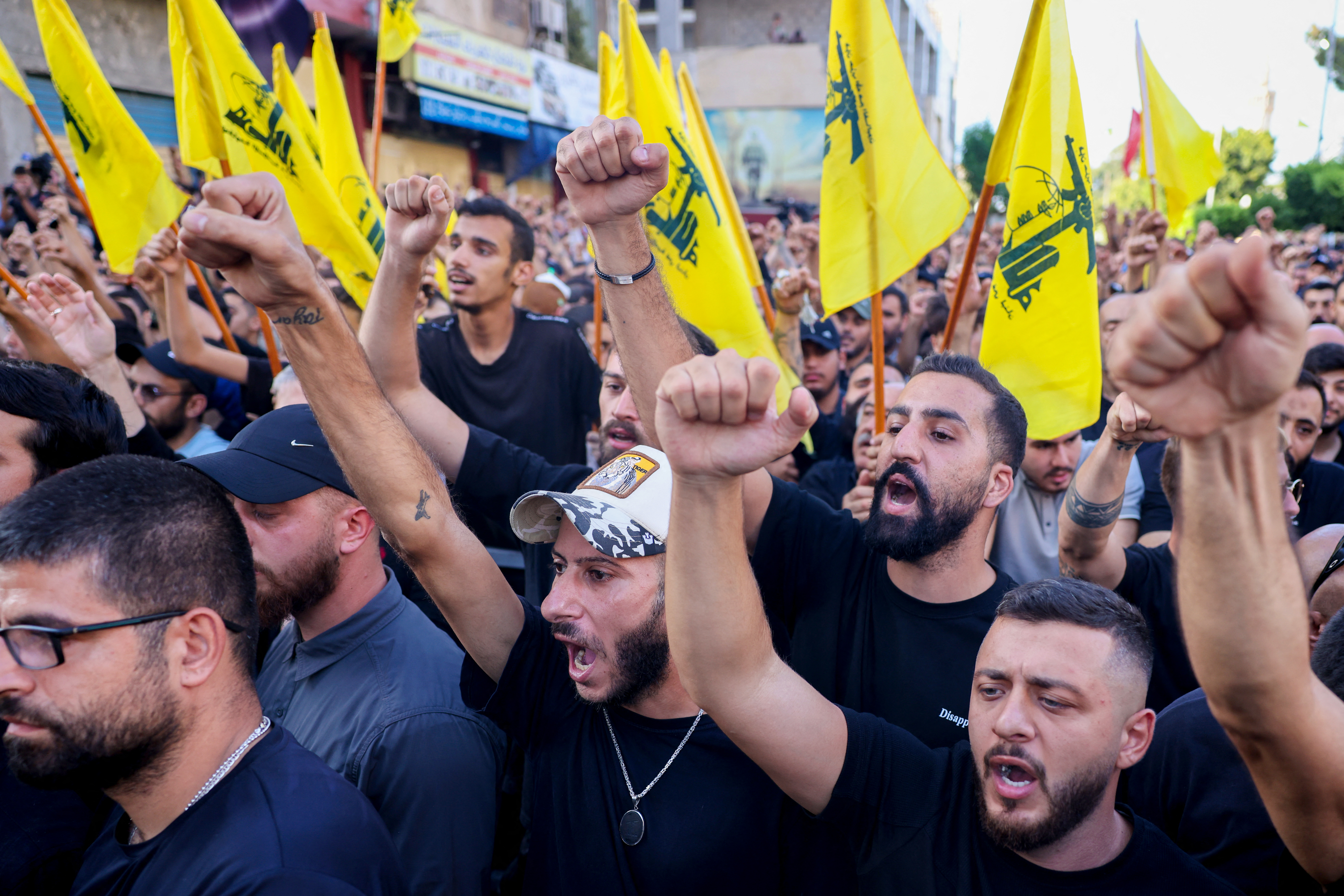 Supporters raise fists and yellow Hezbollah flags