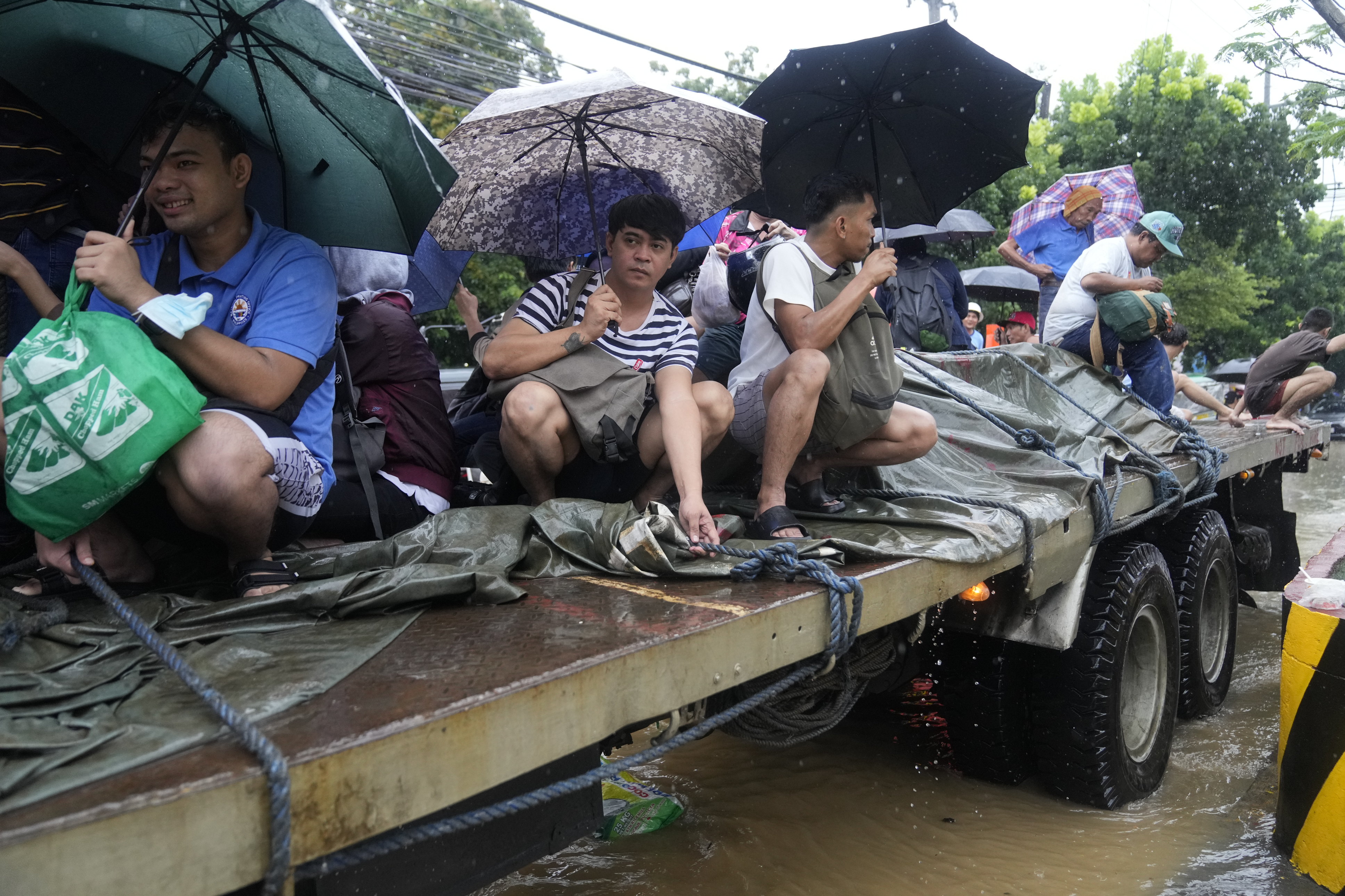 Residents ride a truck as they negotiate a flooded street caused by heavy rains from Tropical Storm Yagi