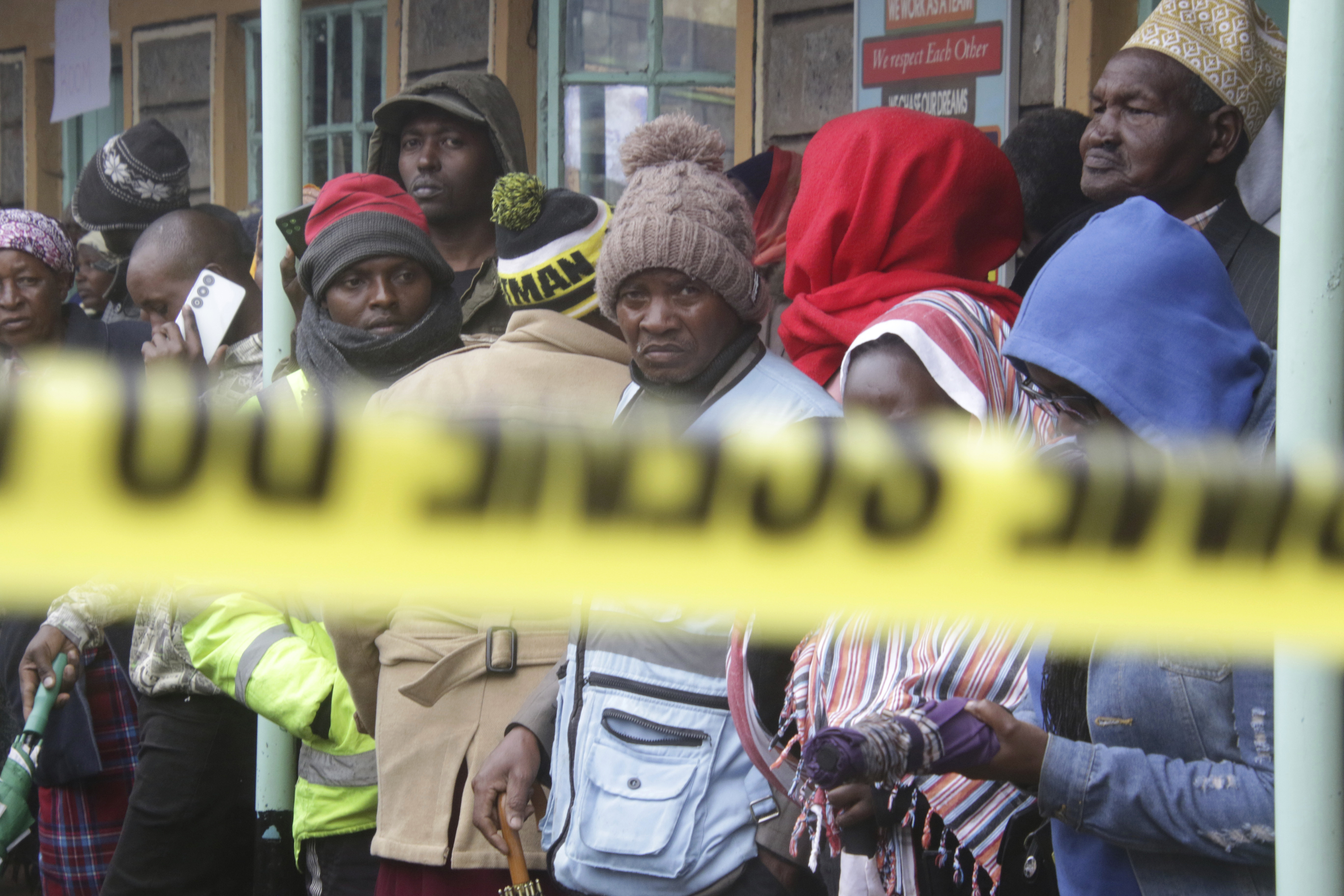 Distressed parents stand near a burnt-out dormitory, following a fire at the Hillside Endarasha Primary in Nyeri, Kenya