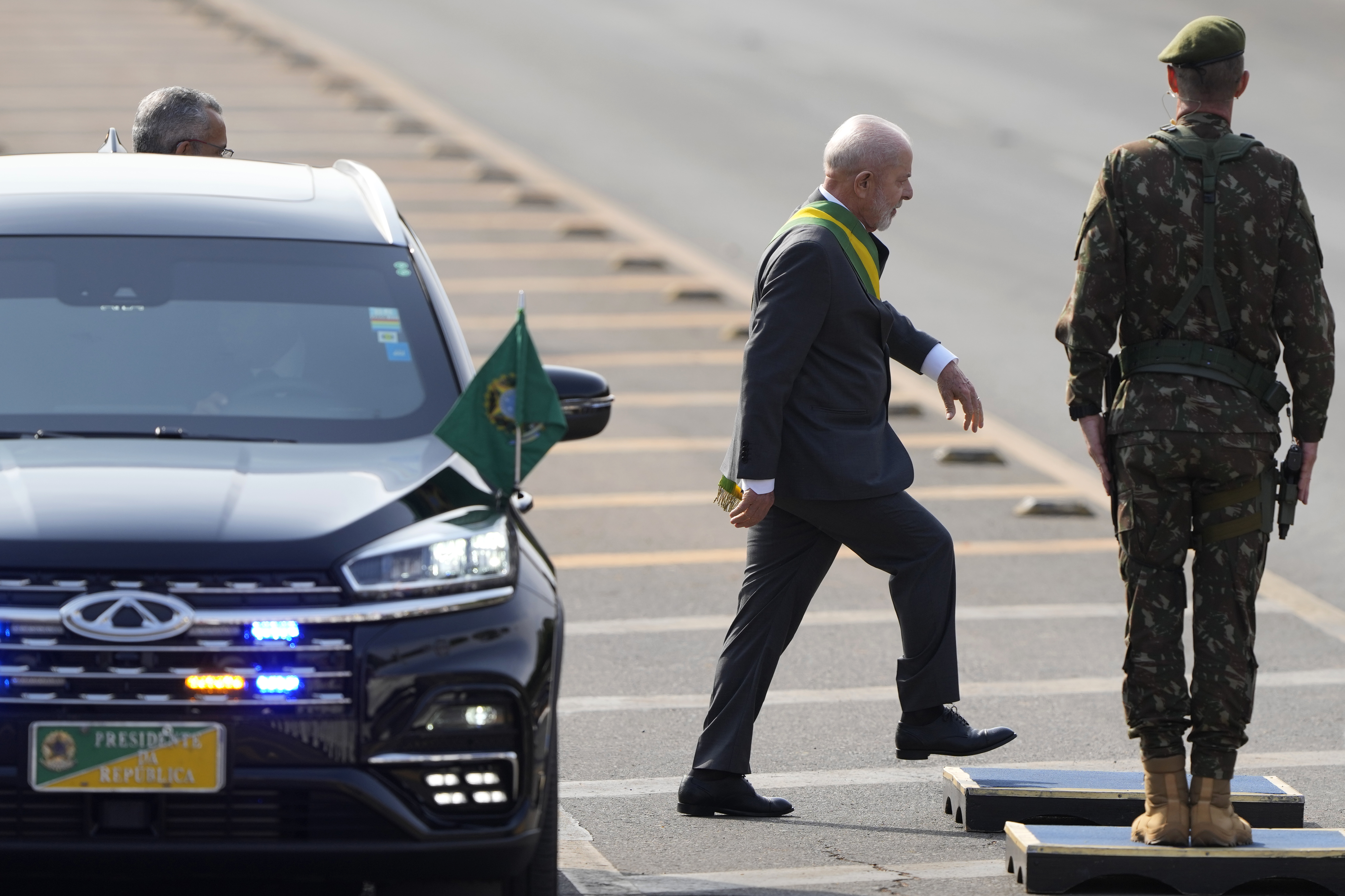 President Lula da Silva exits a black vehicle, as security services stand watch.