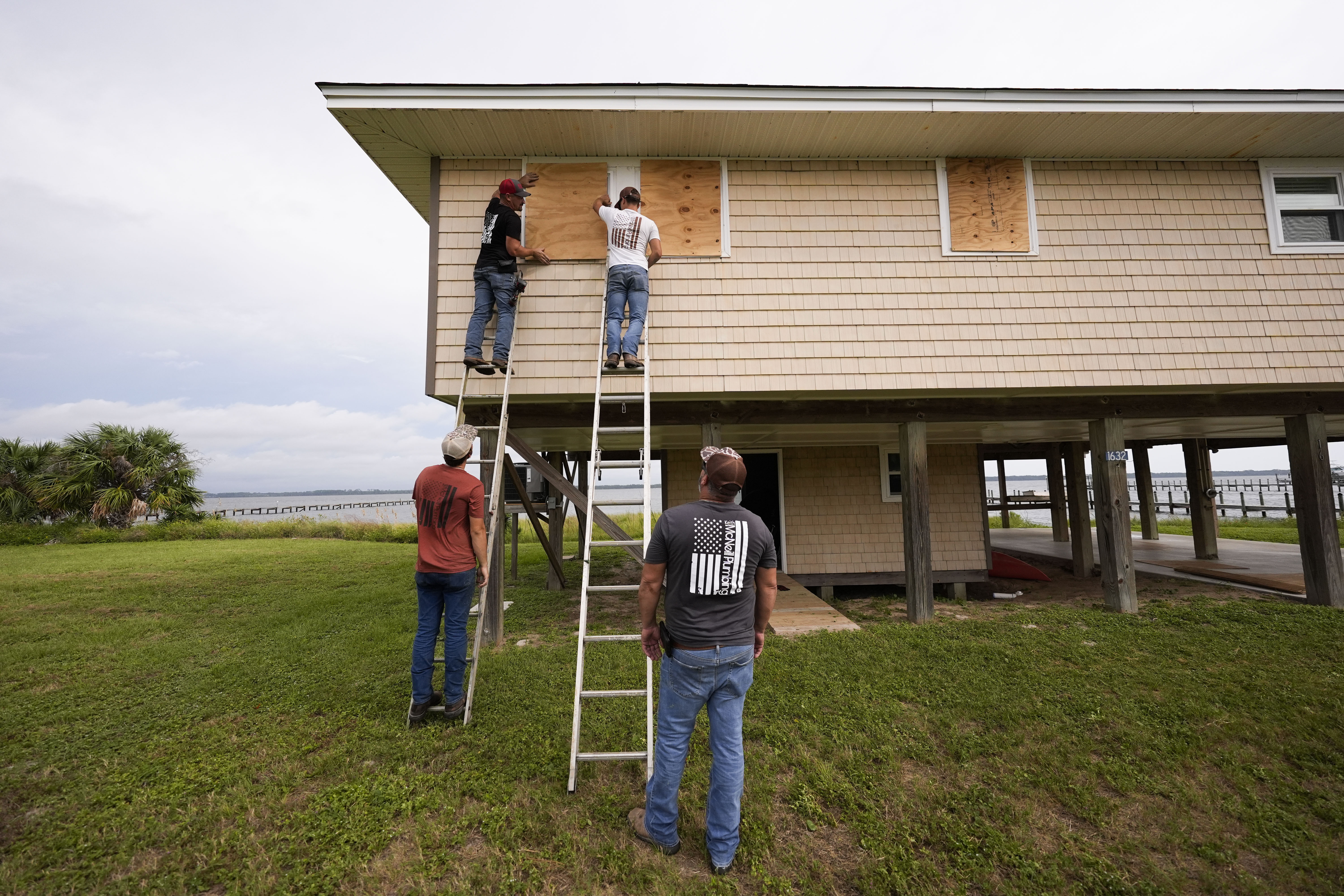 Jerry McCullen, top of ladder left, and Carson Baze, top of ladder right, put plywood over the windows of a house ahead of Hurricane Helene, expected to make landfall Thursday evening, in Alligator Point, Fla., Wednesday, September 25, 2024. [AP Photo/Gerald Herbert]